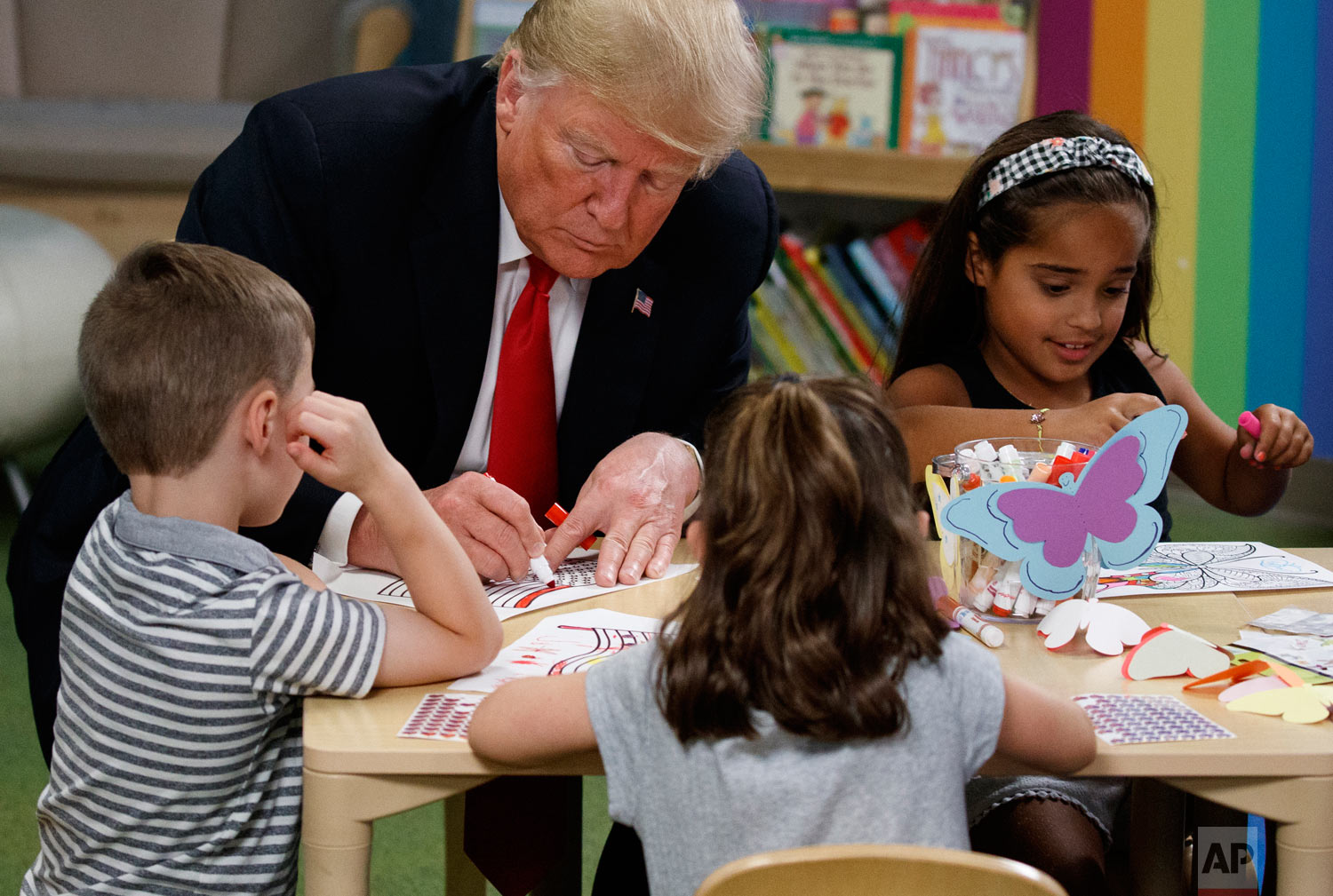 President Donald Trump writes in a coloring book during a visit with a group of children at the Nationwide Children's Hospital, Friday, Aug. 24, 2018, in Columbus, Ohio. (AP Photo/Evan Vucci)
