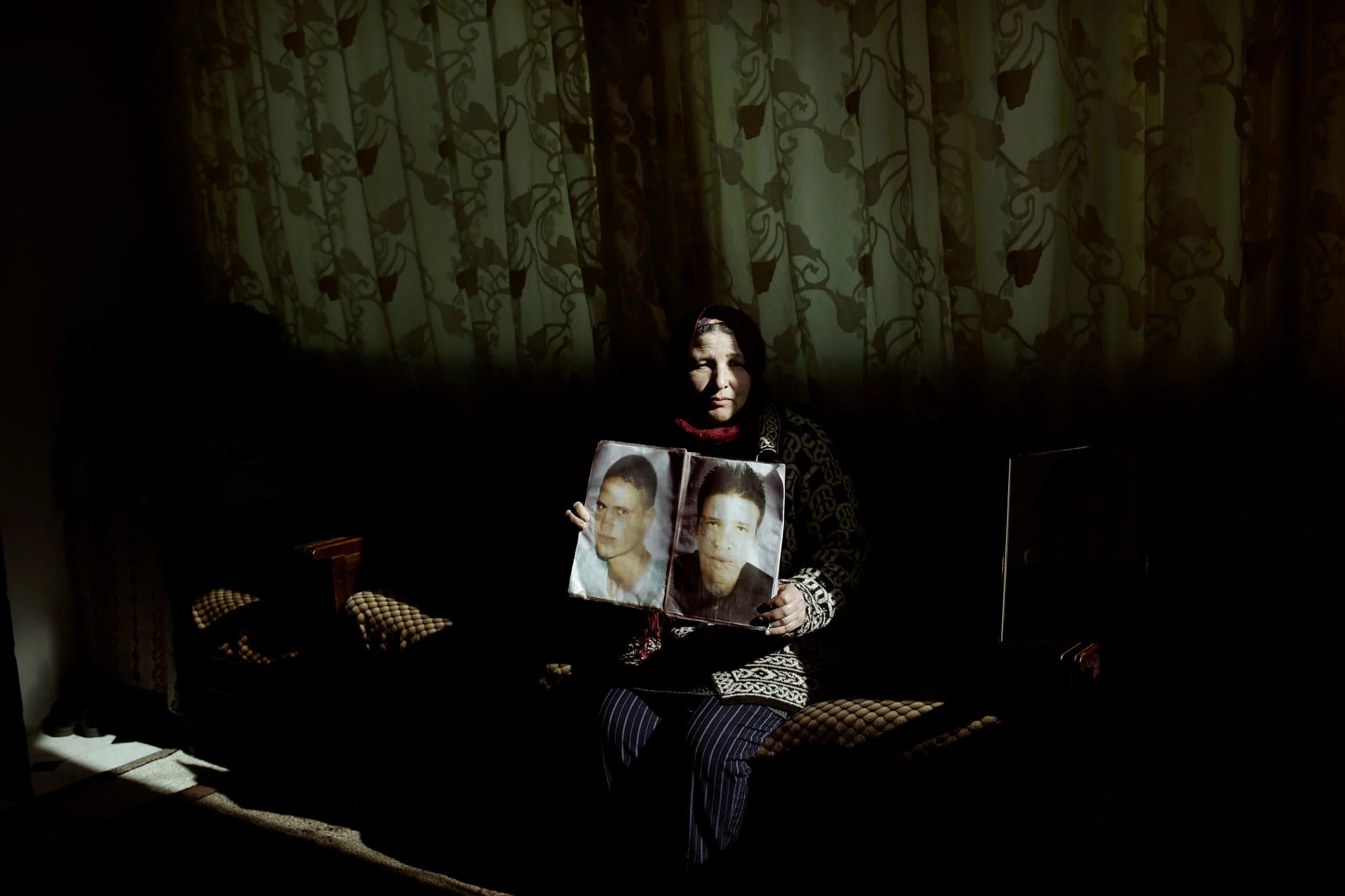 In this Thursday, April 12, 2018 photo, Fathia Jejli holds a photo of her son, Hossam Edin Jejli, right, and her nephew, Hamed Ben Brayek, who went missing in 2011, at her home in the town of Ras Jebel, Tunisia. (AP Photo/Nariman El-Mofty)