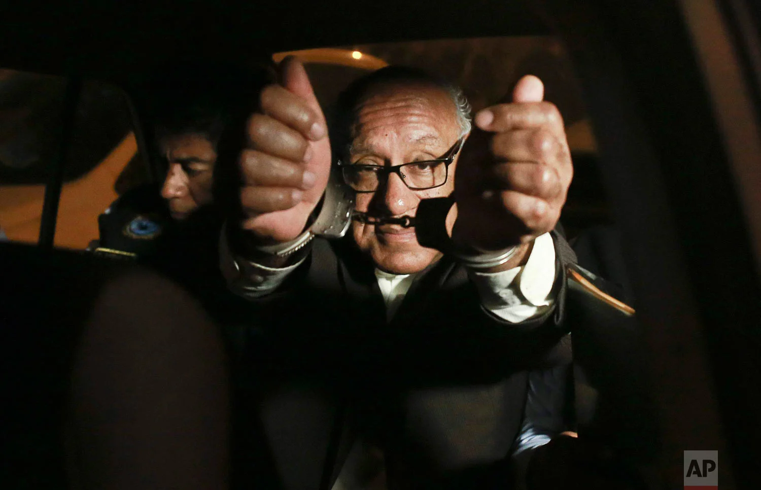 Judge Juan Gonzales shows his handcuffs to the press after he was detained by anti-corruption police in Lima, Peru, Aug. 20, 2018. Gonzalez was detained after allegedly receiving a little more than the equivalent of 1,000 dollars to rule in favor of a group of criminals. (Renzo Salazar/Peru 21 via AP)