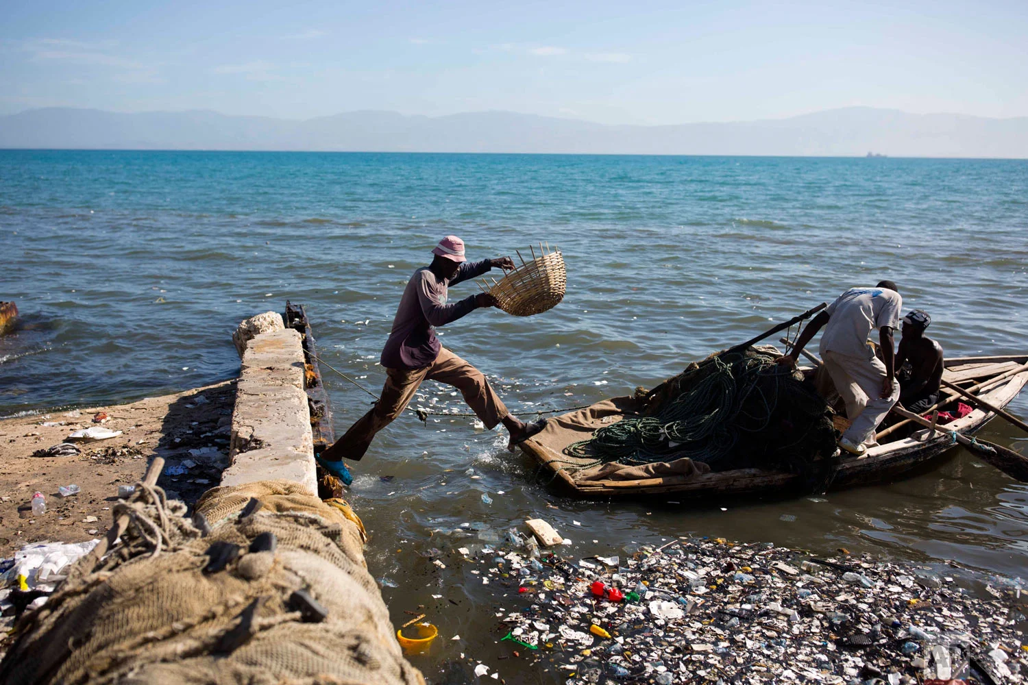 A fisherman jumps on to his wooden boat, joining his mates as they head out to the sea from Port-au-Prince, Haiti, Aug. 13, 2018. (AP Photo/Dieu Nalio Chery)