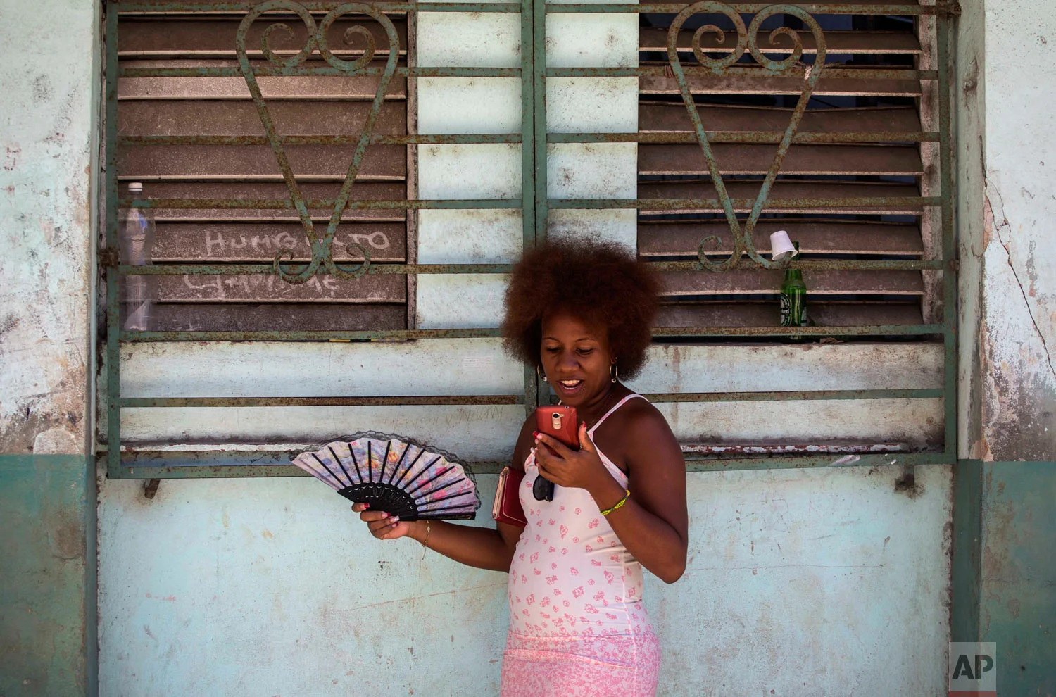 A woman uses her smartphone to surf the internet in Havana, Cuba, Aug. 22, 2018. The state telecommunications company launched on Wednesday the latest, and most extensive, of a recent series of test runs of a mobile network that would give citizens greater access to the internet than has existed before on the island. (AP Photo/Desmond Boylan)