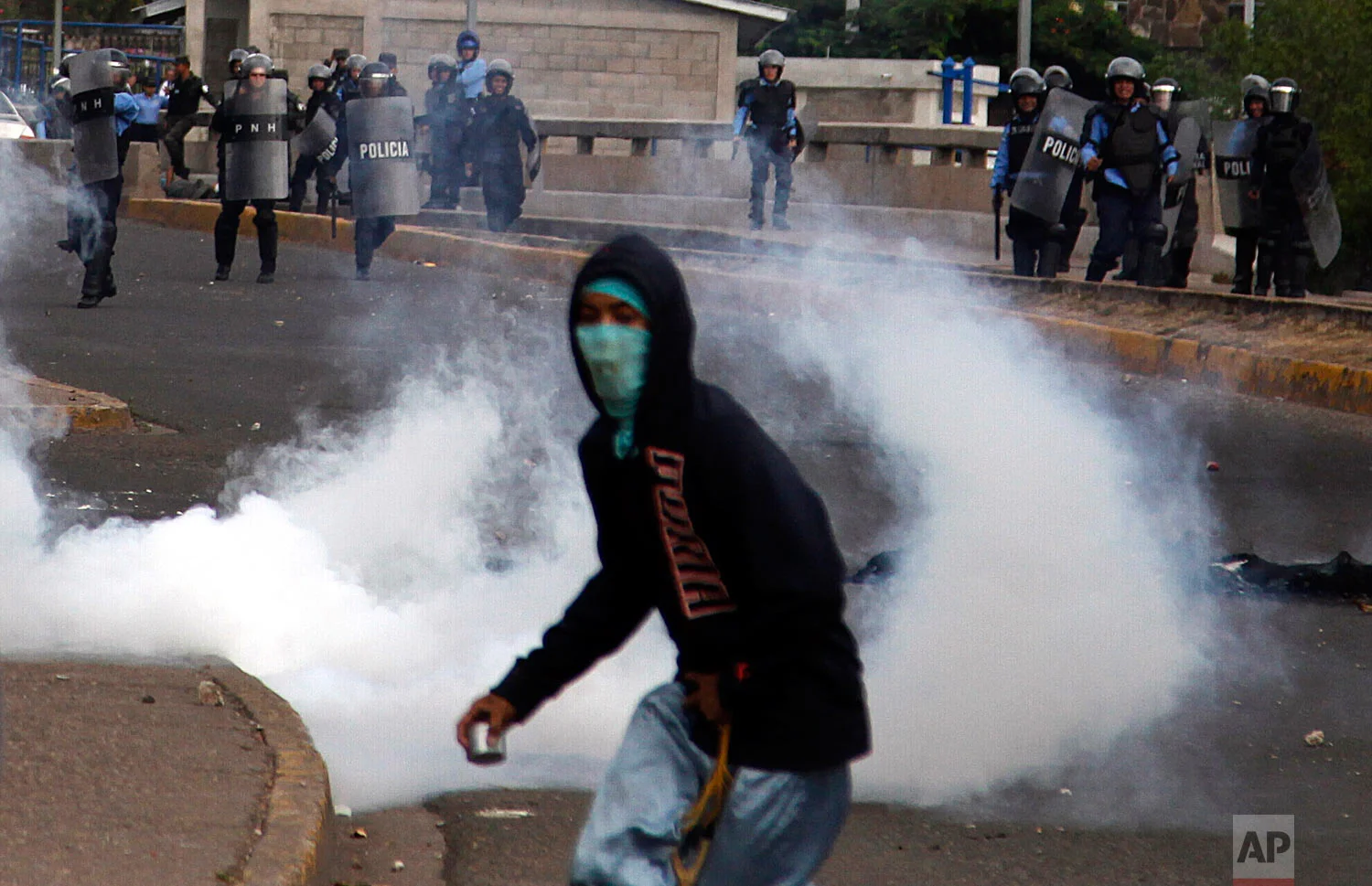 Tear gas explodes around a protestor as university students clash with police while protesting an increase in public transport fares and calling for a drop in the price of gasoline in Tegucigalpa, Honduras, Aug. 1, 2018. Negotiated fare hikes for public transport went into effect on Wednesday. (AP Photo/Fernando Antonio)