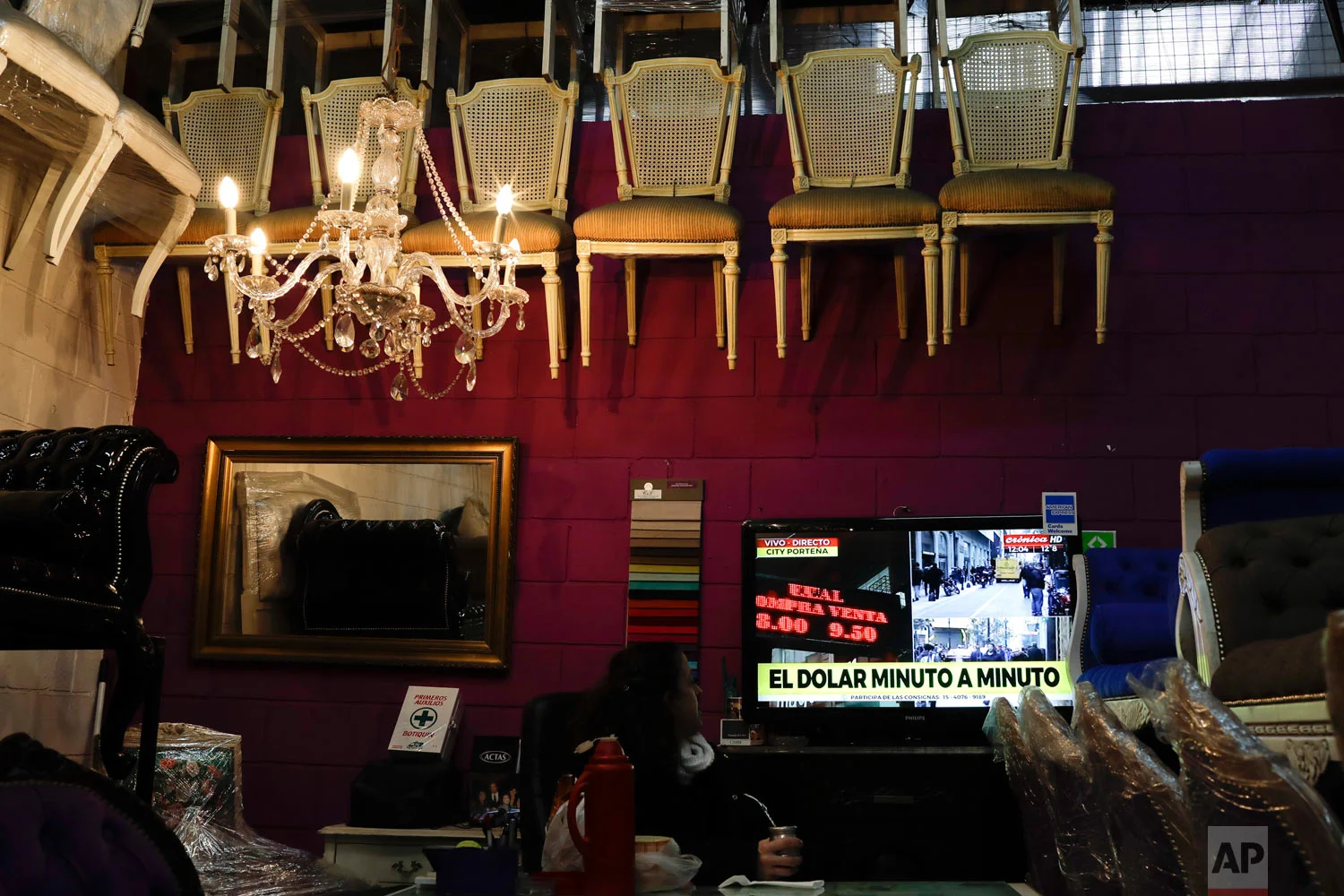 A woman watches news regarding U.S. dollar rates in Buenos Aires, Argentina, Aug. 30, 2018. Argentina's Central Bank on Thursday increased its benchmark interest rate to 60 percent — the world's highest — in an effort to halt a sharp slide in the value of the peso, which plunged to a new record low. (AP Photo/Natacha Pisarenko)