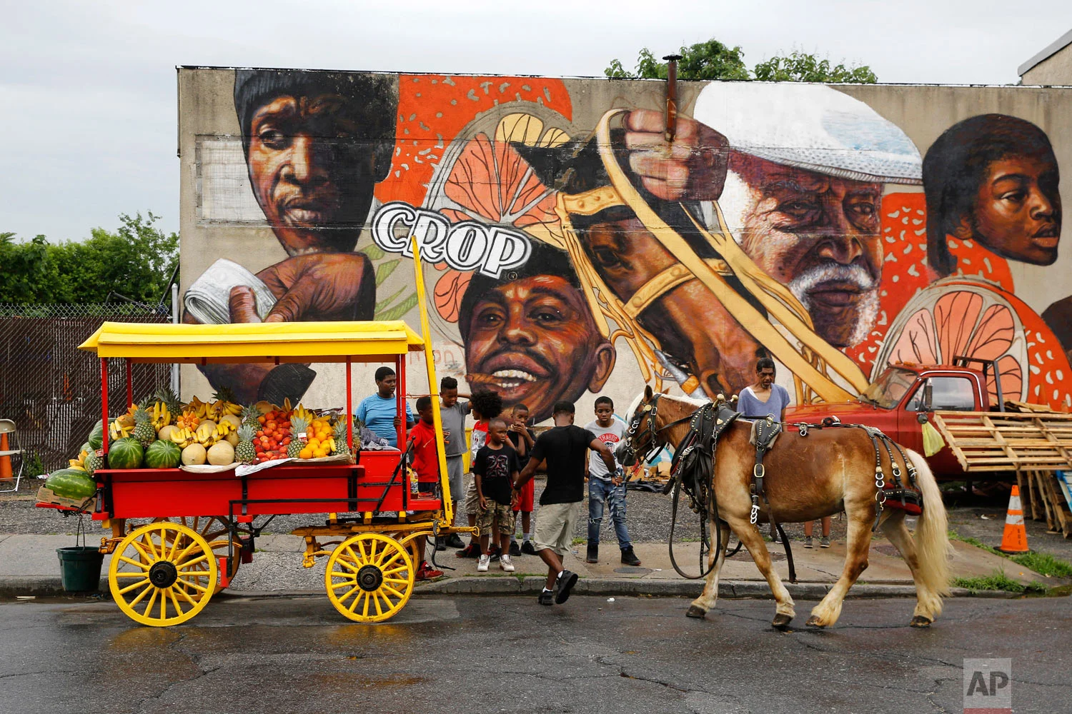 Boys watch as arabber Bilal Yusuf Abdullah prepares his horse-drawn cart full of produce on June 20, 2018, outside a stable in Baltimore. (AP Photo/Patrick Semansky)