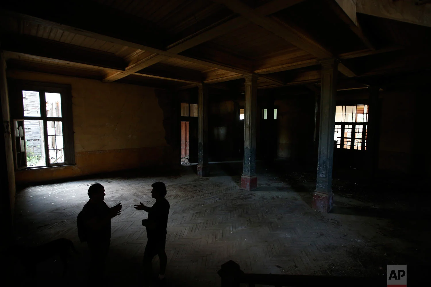 Erol Baytas, 56, caretaker of the 6-floor timber building that once served as an orphanage for children of the minority Greek community, talks to Korhan Gomus, 64, left, an architect and urban planning professor, July 21, 2018, in Buyukada, the largest and most popular of the Princes' Islands in the Sea of Marmara near Istanbul. (AP Photo/Lefteris Pitarakis)