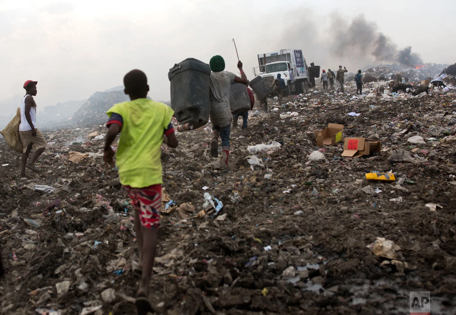People run behind a truck soon to dump its load. Aug. 23, 2018. (AP Photo/Dieu Nalio Chery)