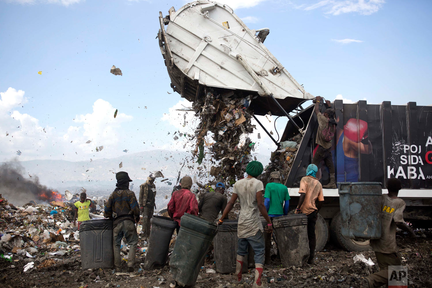  Changlair Aristide, in red shirt at center, waits for a truck to finish dumping its load. Aug. 23, 2018. (AP Photo/Dieu Nalio Chery) 