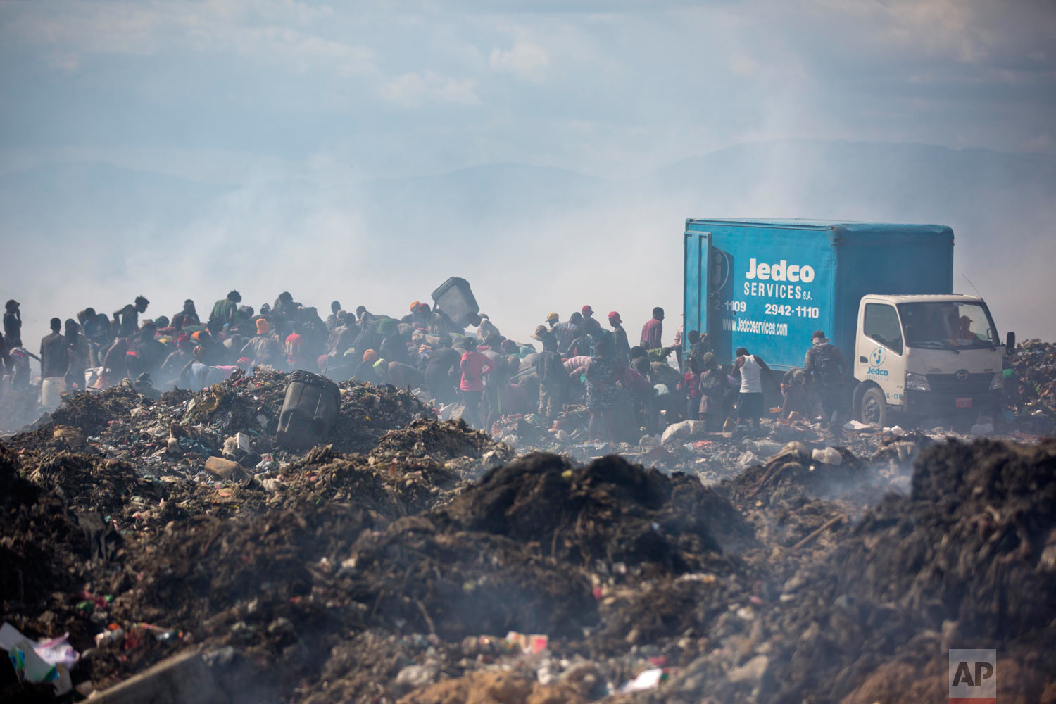  People scavenge behind a truck dumping its load. Aug. 28, 2018. (AP Photo/Dieu Nalio Chery) 