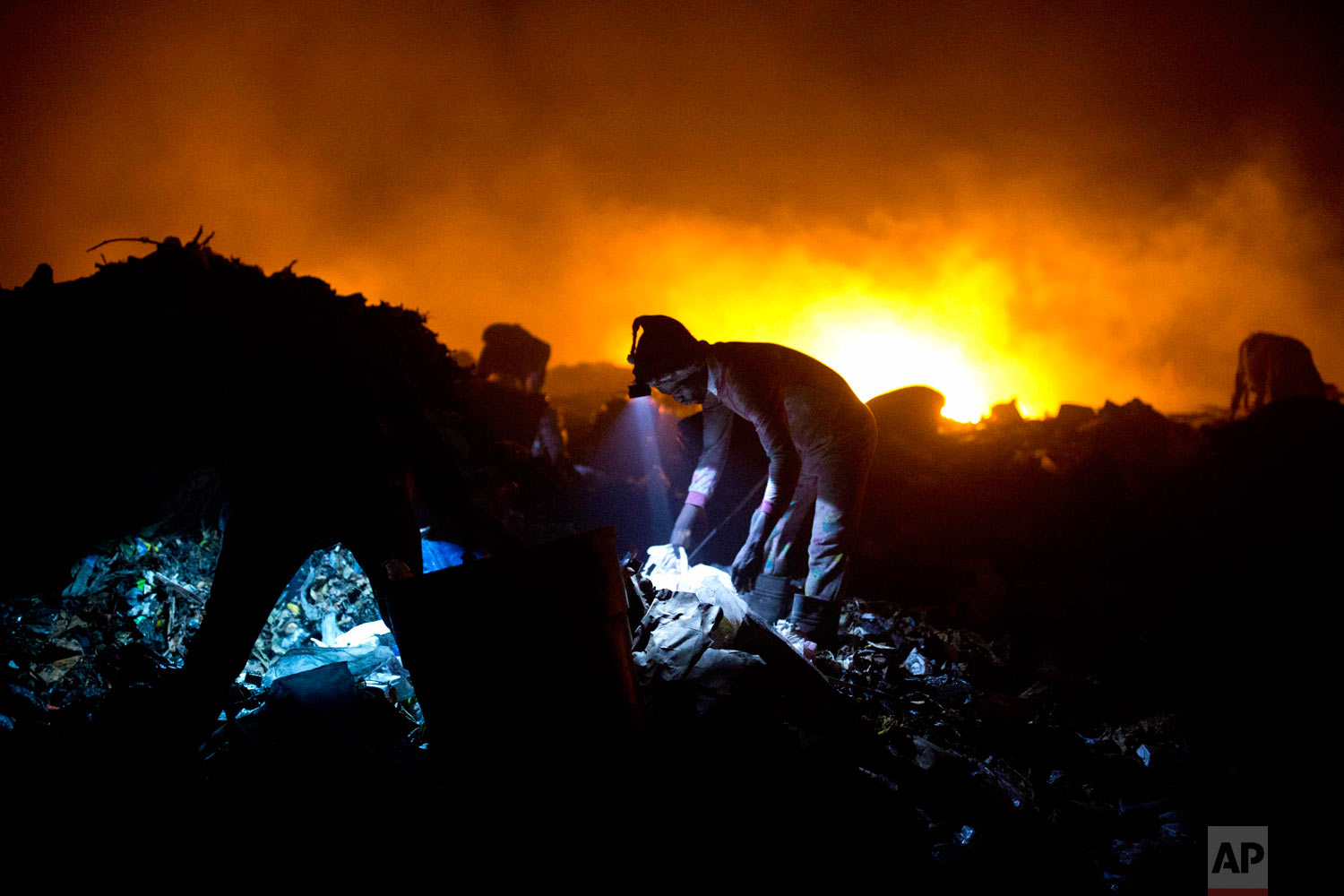  Scavengers use head lamps to continue searching the dump at night. Aug. 30, 2018. (AP Photo/Dieu Nalio Chery) 