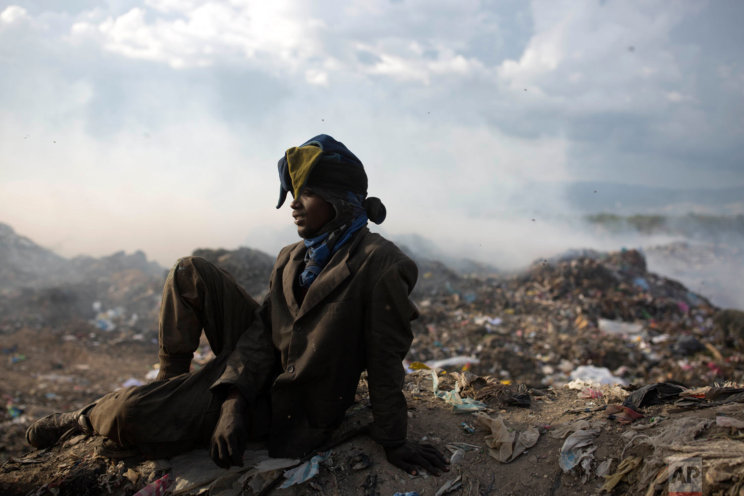  Guerdy Joseph, 24, rests wears a Christmas costume hat he found in the trash, after a work day at the landfill. Joseph has six children, and has been scavenging the dump for the past 10 years. Aug. 30, 2018. (AP Photo/Dieu Nalio Chery) 