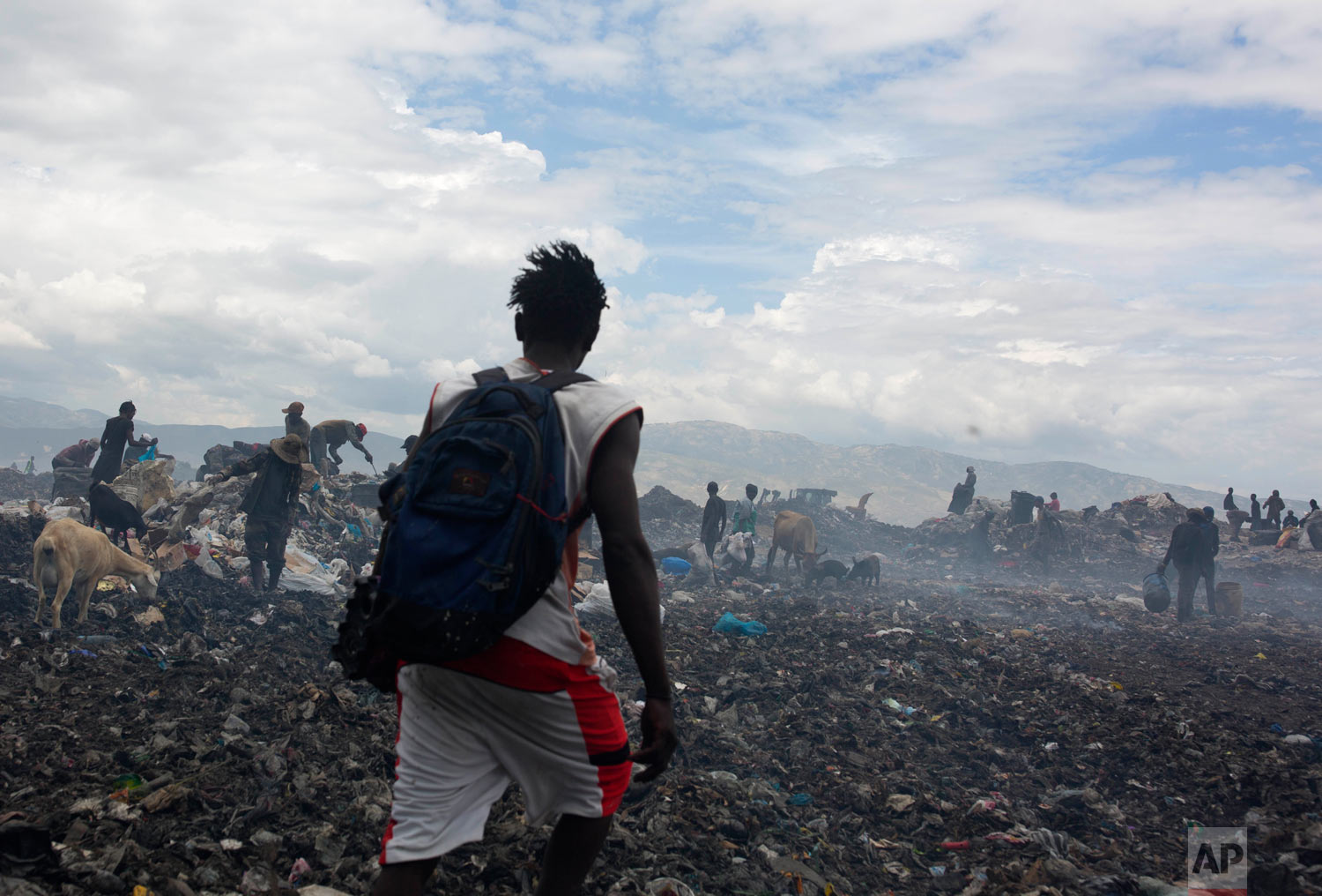  Changlair Aristide crosses the landfill after a day of scavenging trash, as he makes his way to meet with friends. Aug. 27, 2018. (AP Photo/Dieu Nalio Chery) 