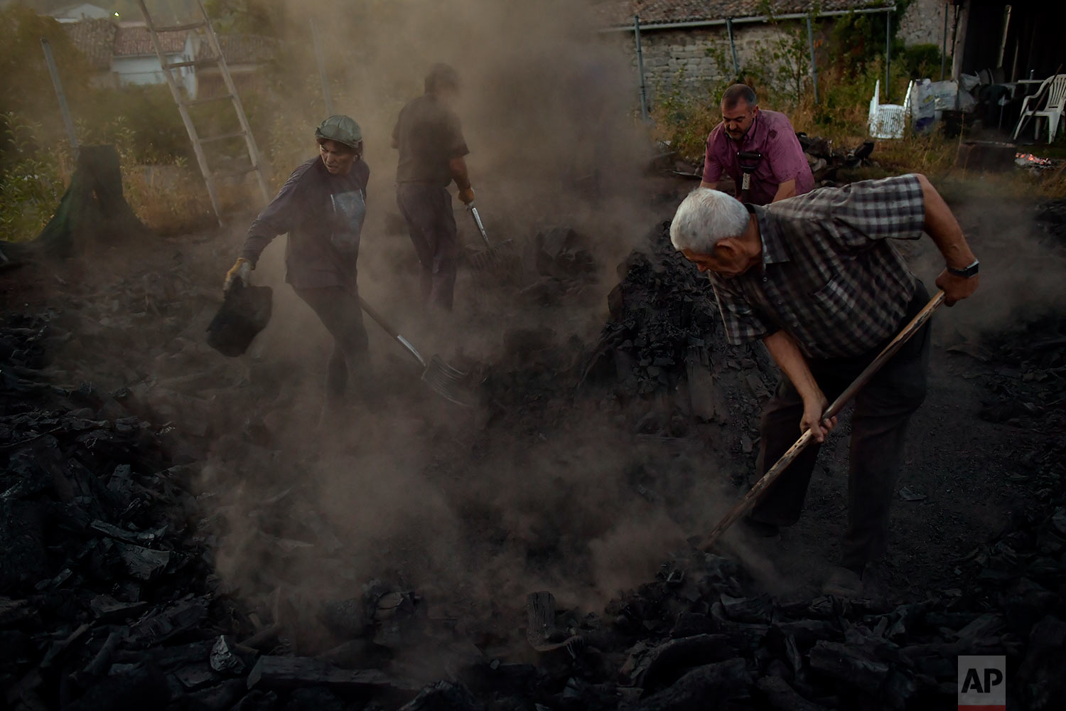  In this Tuesday, Sept.11, 2018 photo, workers extinguish the fire of burning tree trunks, as part of a process to produce traditional charcoal in Viloria, northern Spain. (AP Photo/Alvaro Barrientos) 