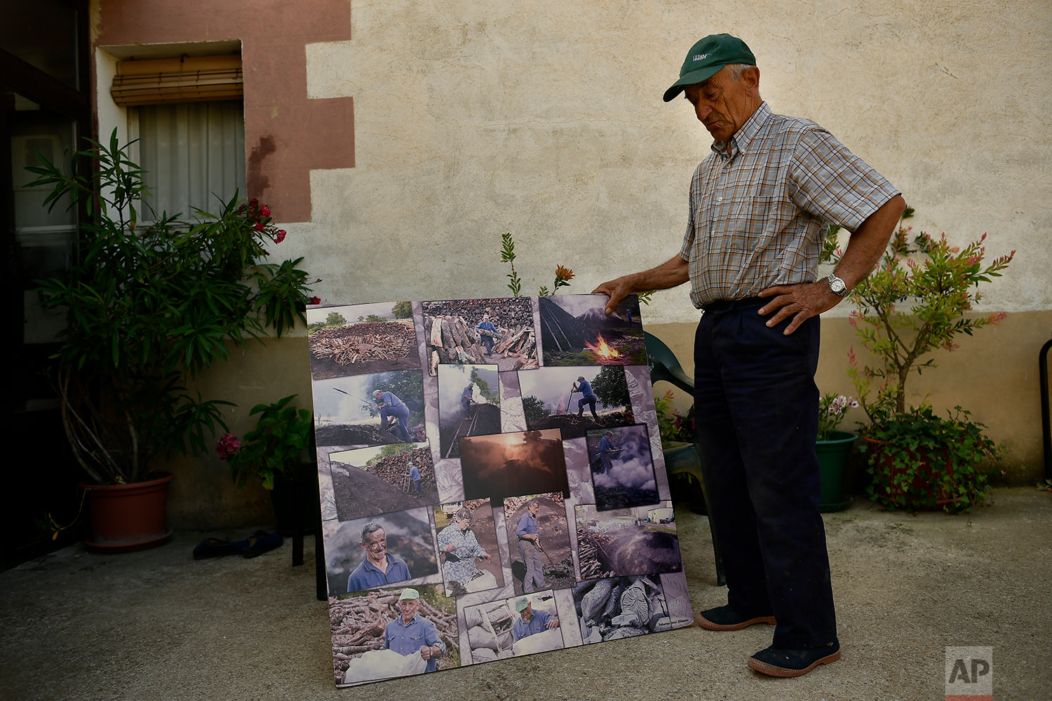  In this Tuesday, Sept.11, 2018 photo, former charcoal worker Emiliano Galdeano, 78, shows some old photographs of himself making traditional charcoal in Viloria, northern Spain.  (AP Photo/Alvaro Barrientos) 