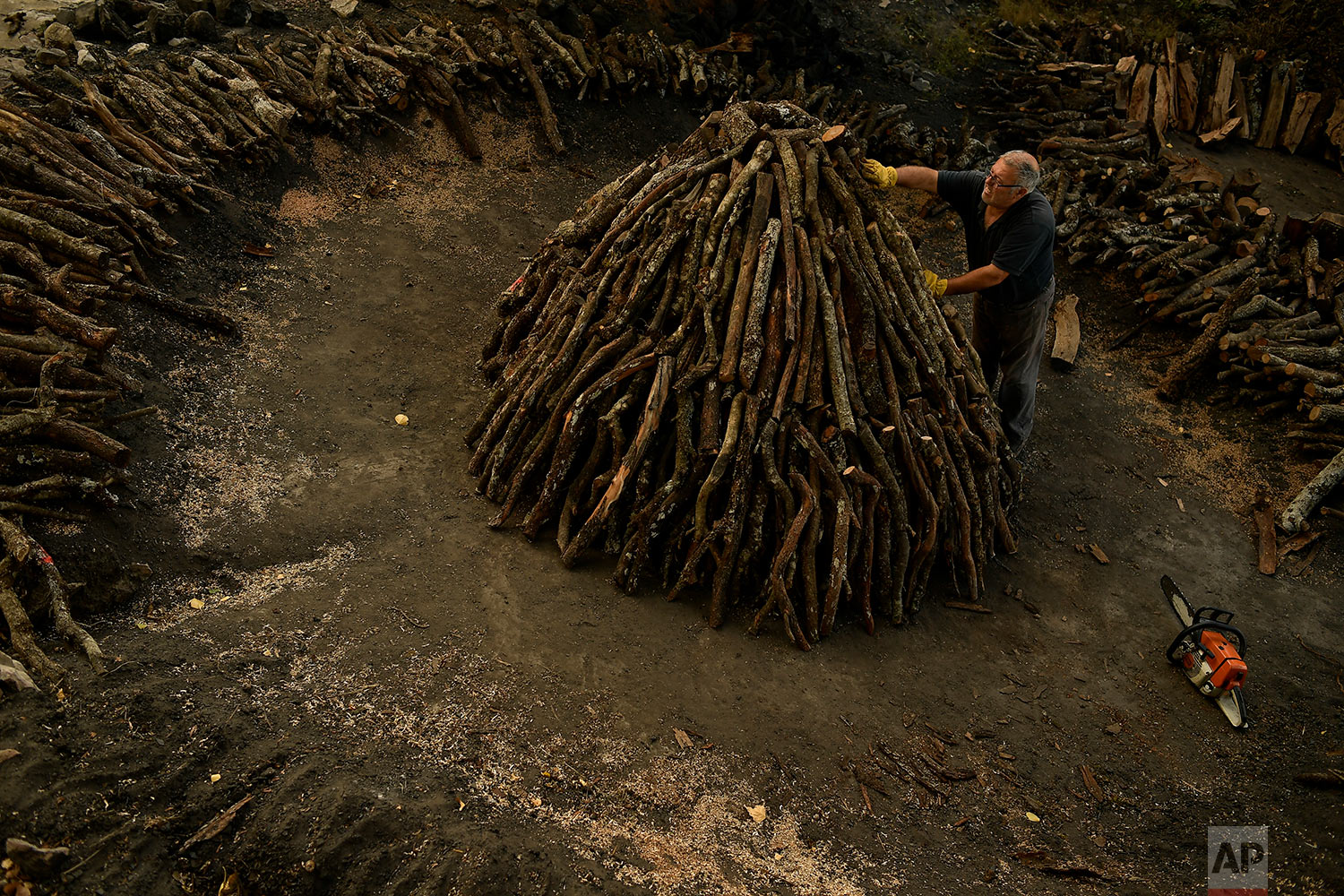  In this Wednesday, Aug. 29, 2018 photo, Jose Mari Nieva, 60, makes a mountain with tree trunks as part of the process to produce traditional charcoal, in the small town of Viloria, northern Spain. (AP Photo/Alvaro Barrientos) 