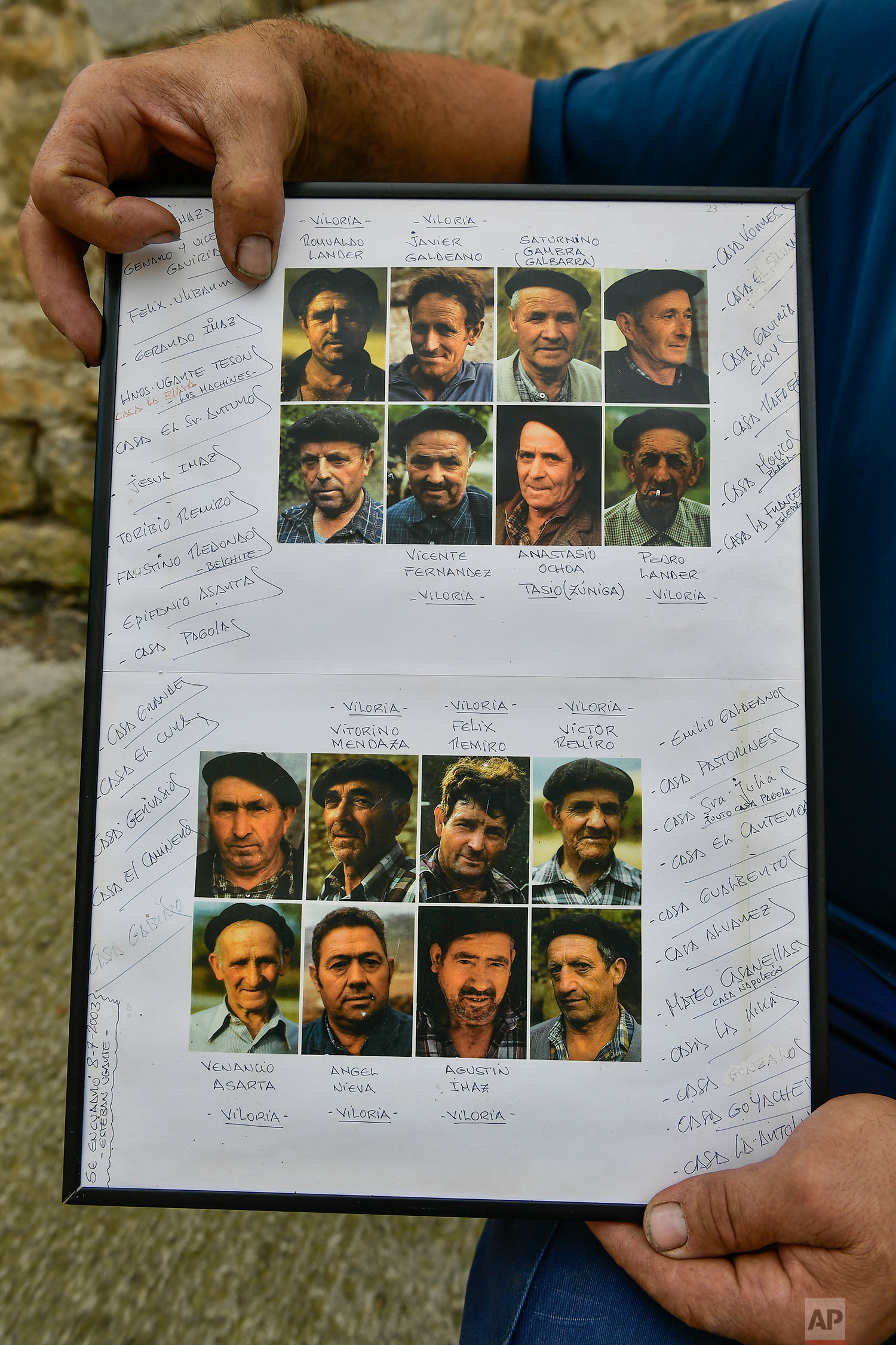 In this Sept.11, 2018 photo, charcoal producer Miguel Lander, 56, holds a picture with portraits of former charcoal producers in Viloria, northern Spain. (AP Photo/Alvaro Barrientos)