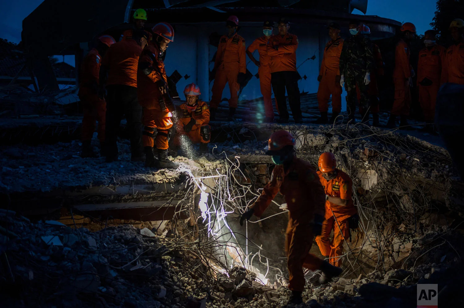 Rescuers search for victims feared buried under the rubble of a building, flattened by an earthquake in Tanjung, Lombok Island, Indonesia, Monday, Aug. 6, 2018. (AP Photo/Fauzy Chaniago)