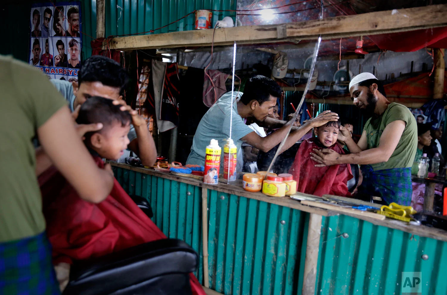 A Rohingya refugee child cries as he gets a hair cut at a makeshift saloon at Balukhali Refugee Camp in Bangladesh, Monday, Aug. 27, 2018. (AP Photo/Altaf Qadri)