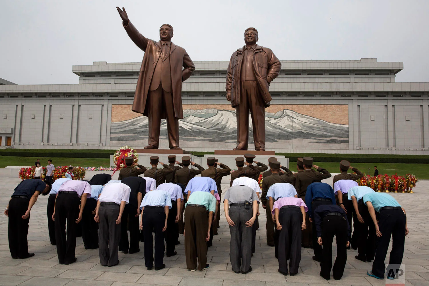 North Korean soldiers salute as others bow before the giant bronze statues of late North Korean leaders Kim Il Sung and Kim Jong Il during the anniversary of the end of World War II and liberation from Japanese colonial rule in Pyongyang, North Korea, Wednesday, Aug. 15, 2018. (AP Photo/Ng Han Guan)