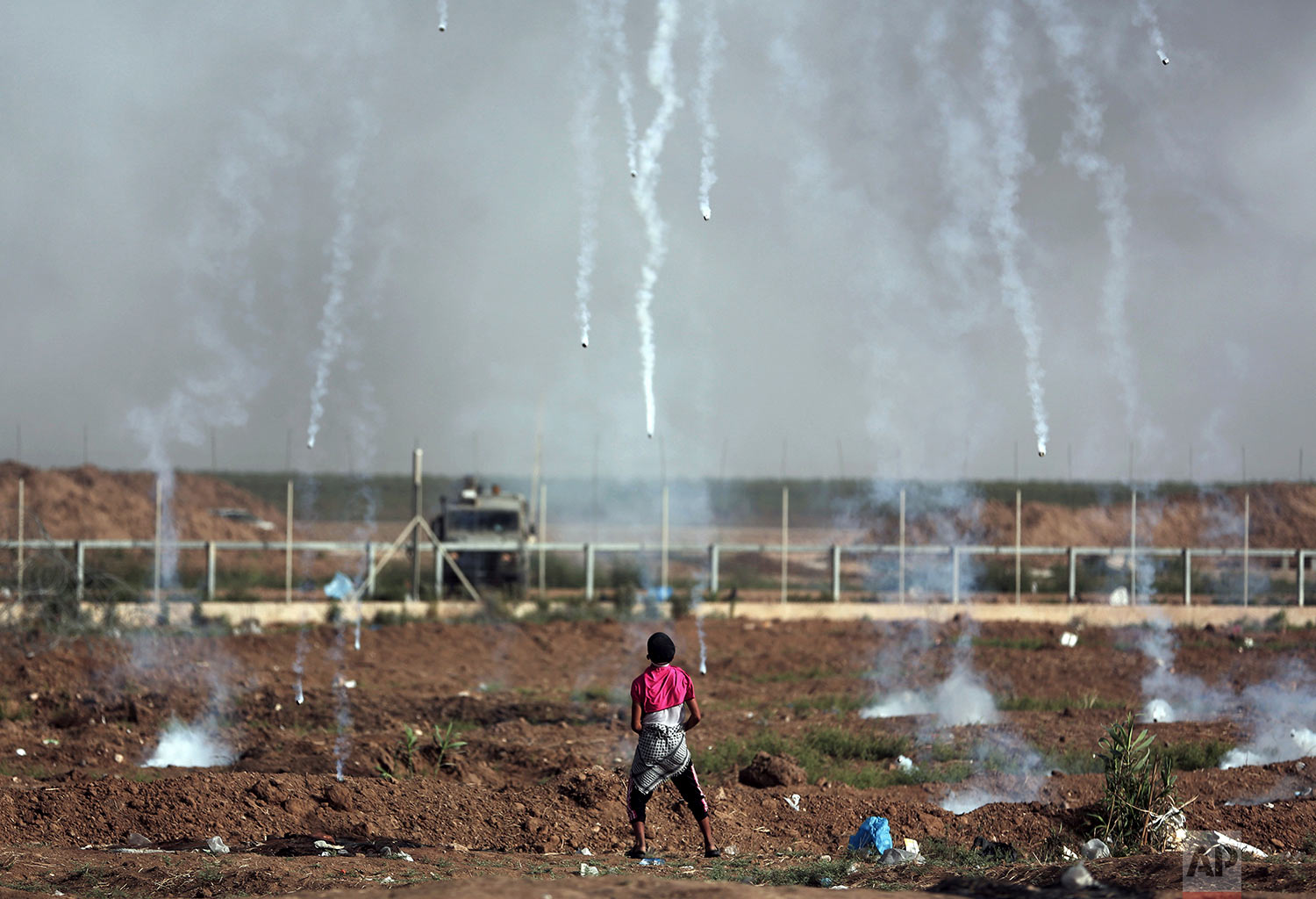  In this May 25, 2018 photo, teargas canisters fired by Israeli troops fall around a Palestinian youth during a protest at the Gaza Strip's border with Israel. (AP Photo/Khalil Hamra) 