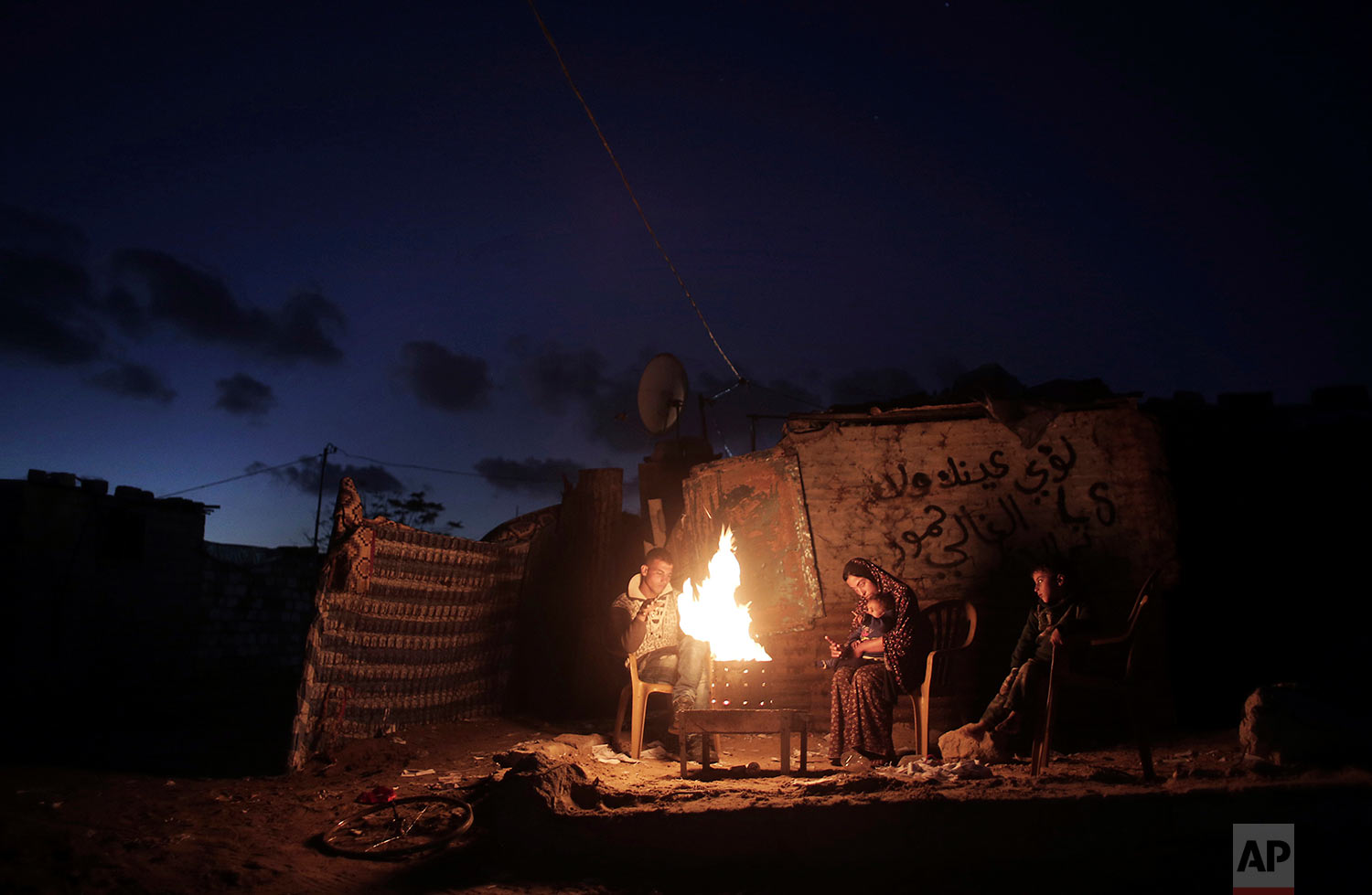  In this Jan. 15, 2017 photo, a Palestinian family warm themselves with a fire outside their makeshift house during a power cut in a poor neighborhood in Khan Younis, the southern Gaza Strip. (AP Photo/Khalil Hamra) 