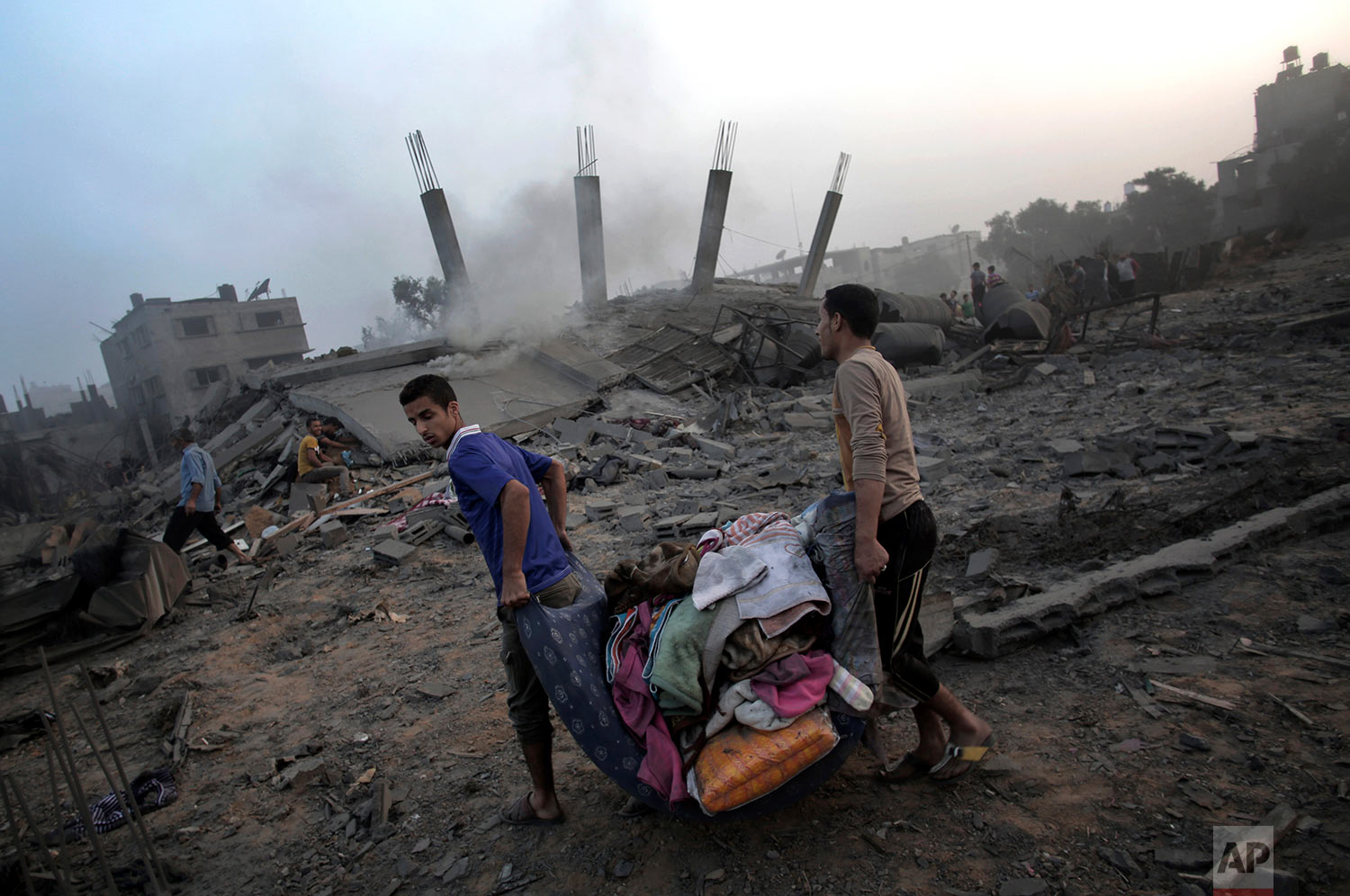  In this July 8, 2014 photo, Palestinians try to salvage what they can of their belongings from the rubble of a house destroyed by an overnight Israeli airstrike in Gaza City. (AP Photo/Khalil Hamra) 