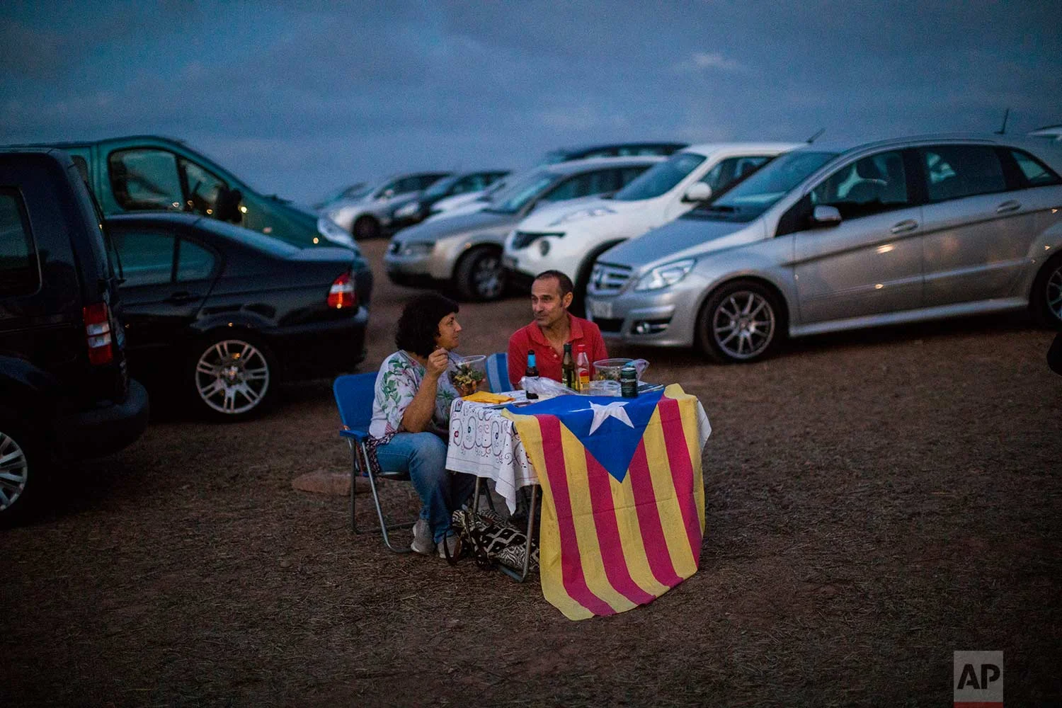 In this Tuesday, Sept. 18, 2018 photo, pro independence people enjoy a picnic on a field overlooking the Lledoners prison, in Sant Joan de Vilatorrada, about 50 kilometres away from Barcelona, Spain. (AP Photo/Emilio Morenatti)