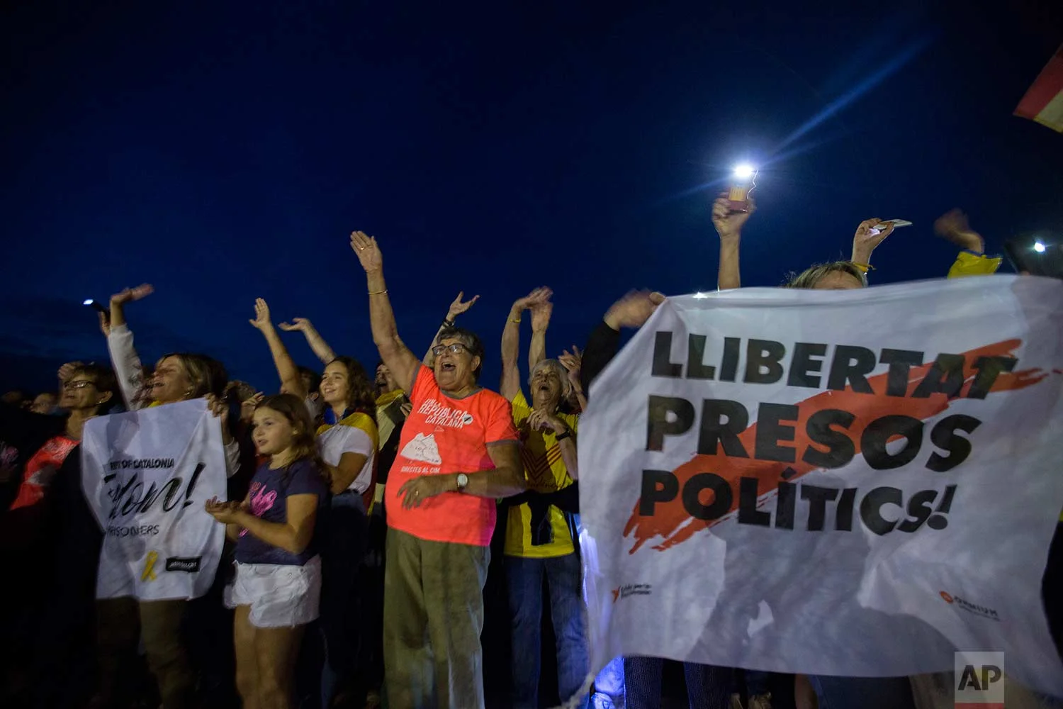 In this Tuesday, Sept. 18, 2018 photo, pro independence supporters react as an "estelada" or independence flag waves from the window of a cell in nearby Lledoners prison, in Sant Joan de Vilatorrada, about 50 kilometres away from Barcelona, Spain. (AP Photo/Emilio Morenatti)