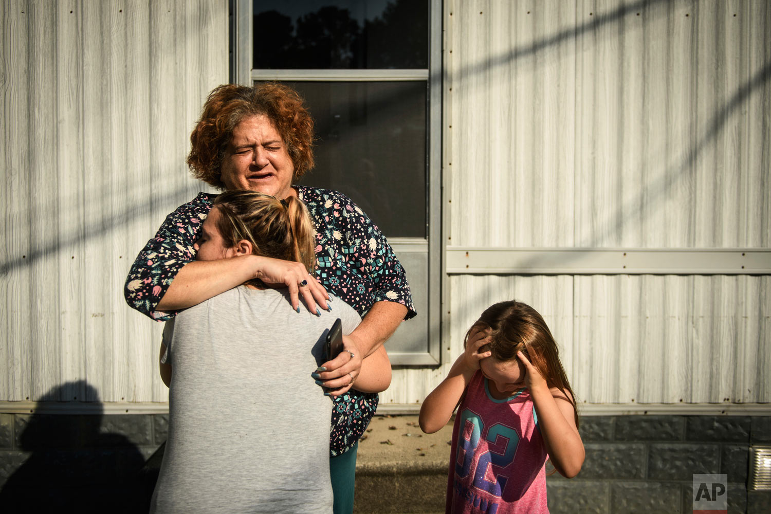  Melanie Wensel gives her neighbor Linda Remmel a hug as Wensel's daughter, Emily, stands near, Thursday, Sept. 20, 2018, at Speranza Mobile Home Park off of Manchester Road in Spring Lake, N.C. Most of the residents of the park had their homes flood