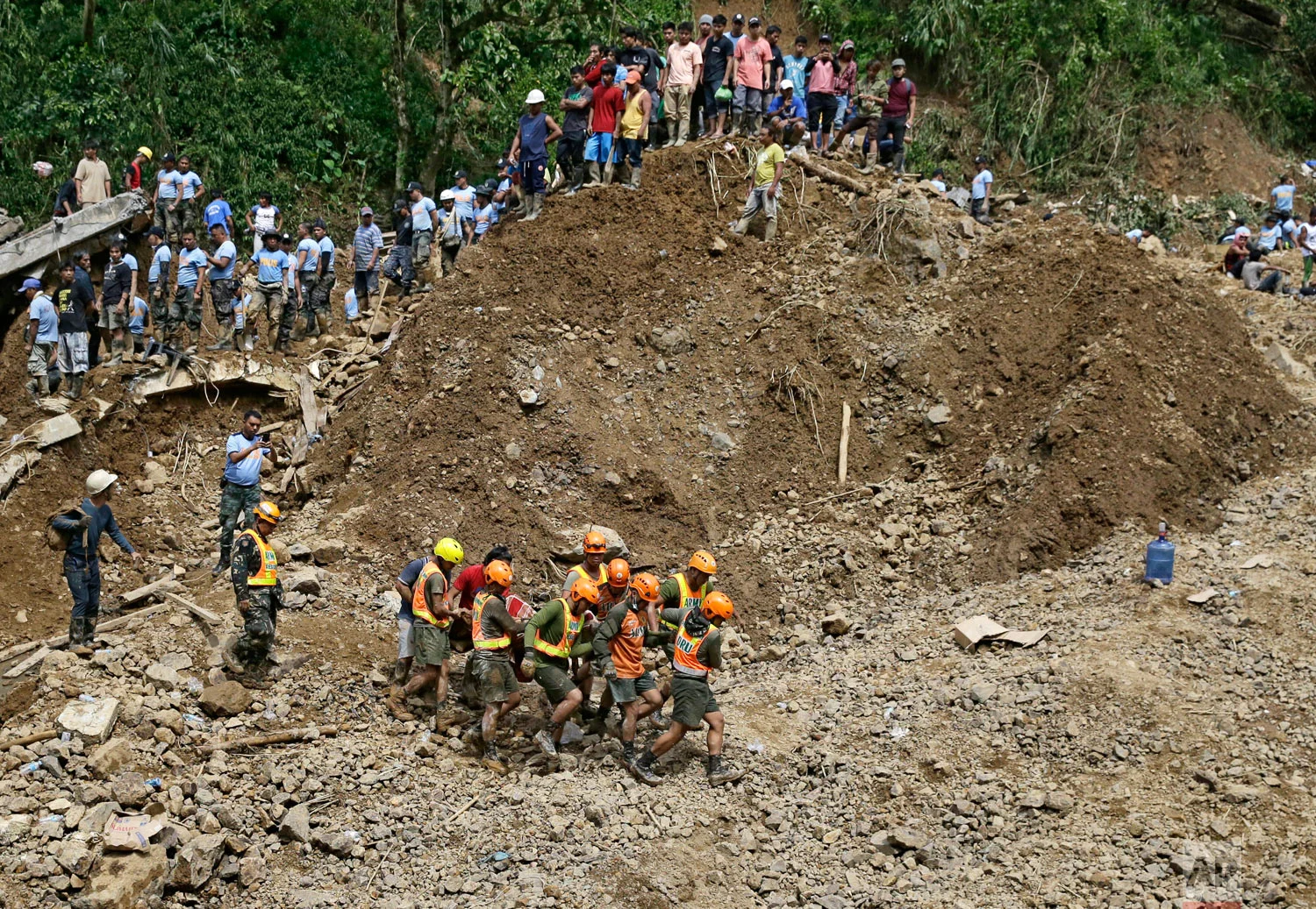 Rescuers carry a body they recovered at the site where victims are believed to have been buried by a landslide after Typhoon Mangkhut lashed Itogon, Benguet province, northern Philippines on Monday, Sept. 17, 2018. Itogon Mayor Victorio Palangdan said that at the height of the typhoon's onslaught Saturday afternoon, dozens of people, mostly miners and their families, rushed into an old three-story building in the village of Ucab. The building, a former mining bunkhouse that had been transformed into a chapel, was obliterated when part of a mountain slope collapsed. (AP Photo/Aaron Favila)