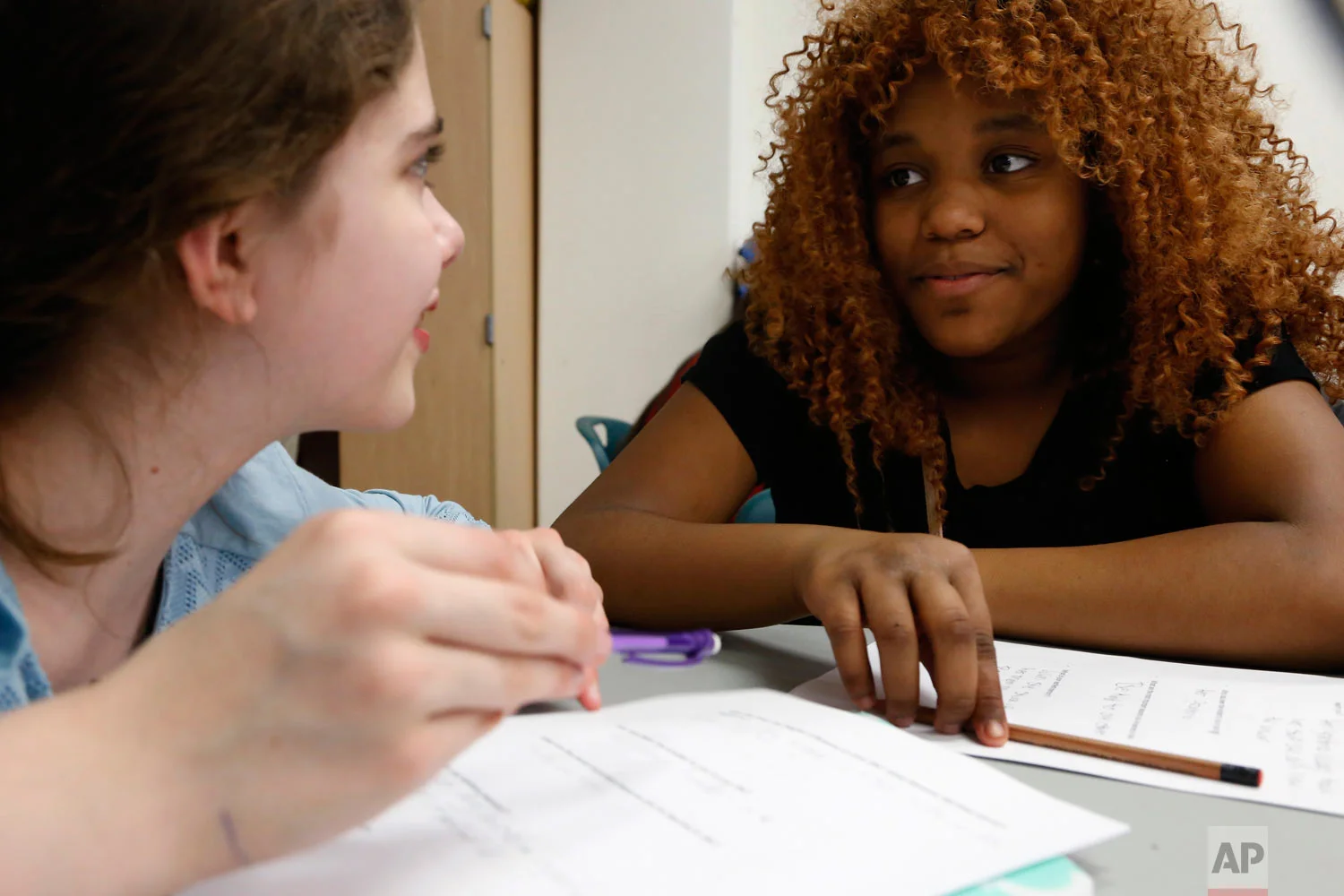In this April 27, 2017, photo, Miracle Shanklin, right, and Isabella Iniguez, both age 12 when this photo was taken, talk during an ice-breaker exercise in Chicago. The session brought together students from the public Manierre Elementary School and the private Catherine Cook School - on opposite sides of Sedgwick Street. (AP Photo/Martha Irvine)