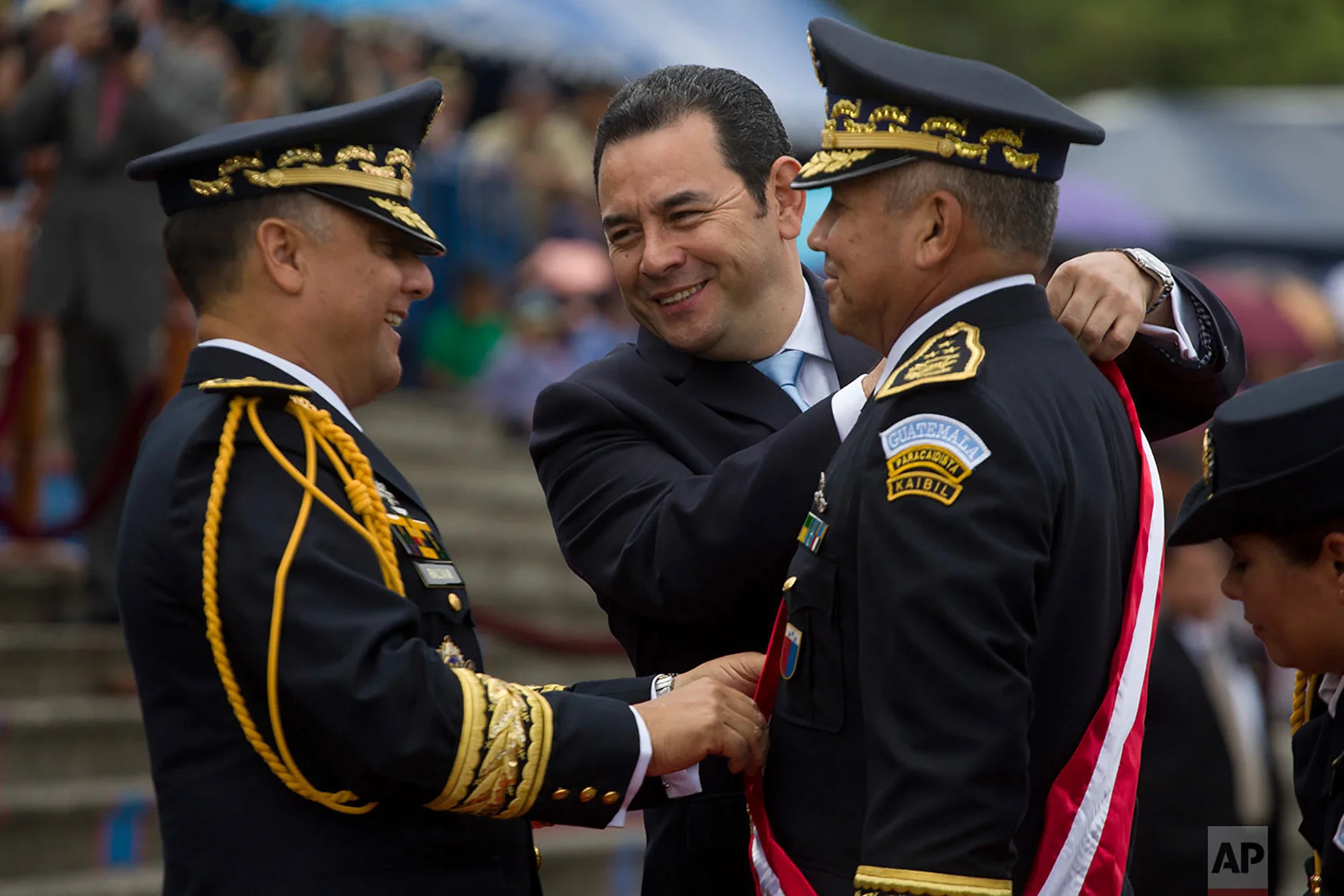 Guatemalan President Jimmy Morales center, places a sash on general Manuel Pineda Saravia, right, during the 145th anniversary of the Military school in San Juan Sacatepequez, Guatemala, Sept. 1, 2018. Morales announced Friday that he is shutting down a crusading U.N.-sponsored anti-graft commission that pressed a number of high-profile corruption probes, including one pending against the president himself over purported illicit campaign financing. (AP Photo/Moises Castillo)