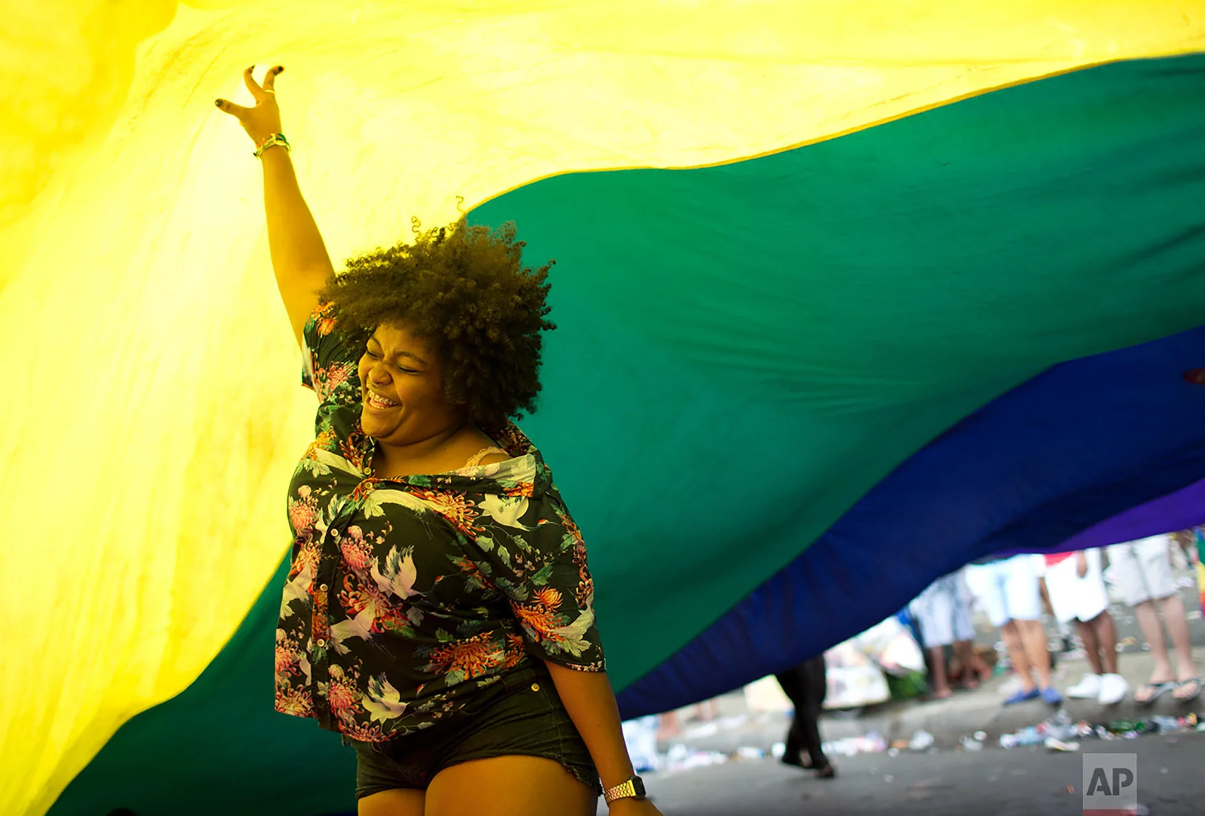 A woman dances under a giant rainbow flag during the annual Gay Pride Parade along Copacabana beach in Rio de Janeiro, Brazil, Sept. 30, 2018. One week before Brazil's presidential elections, organizers coined the theme of the parade "Vote for ideas and not for people," aiming to encourage people to vote for candidates who support gay and human rights. (AP Photo/Silvia Izquierdo)