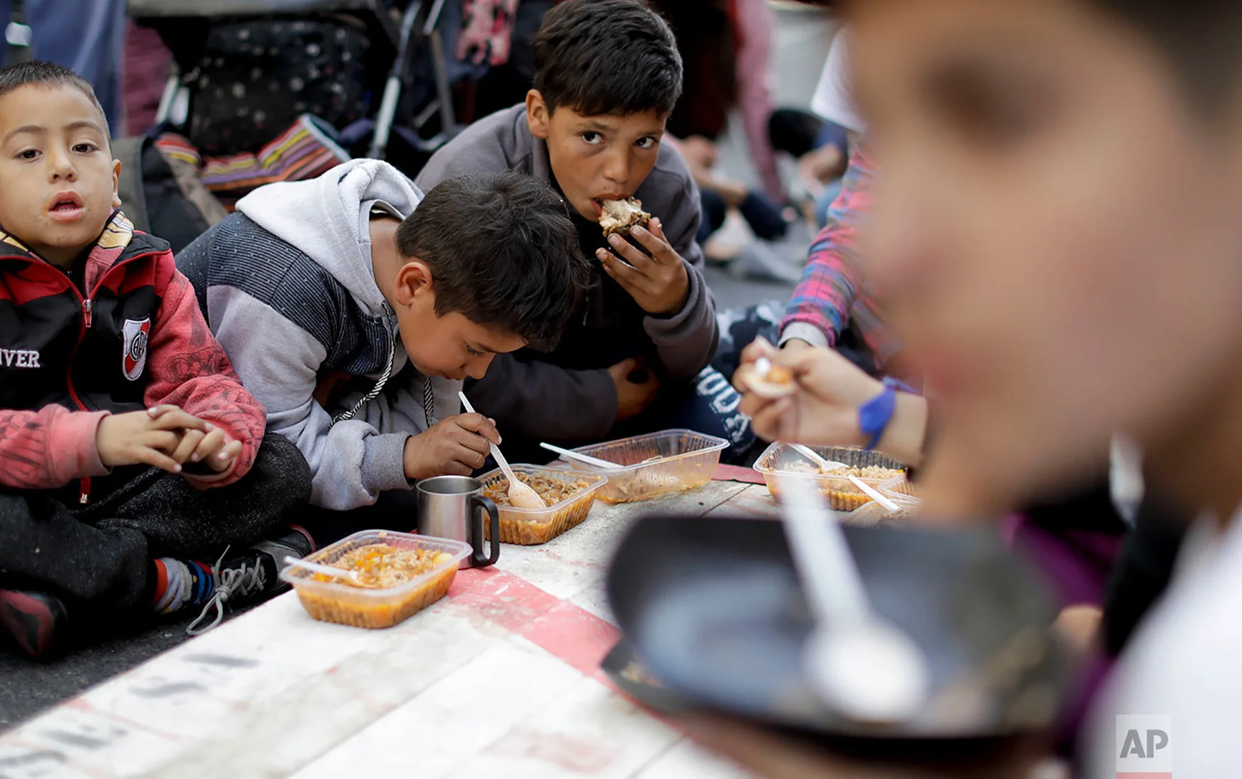 Children eat free food where demonstrators set up a soup kitchen along a main avenue that connects the government house with Congress as a way to protest government economic measures in Buenos Aires, Argentina, Sept. 11, 2018. Consumer prices are soaring, unemployment is high and the Argentine peso has plunged, bringing back haunting memories of the country's economic meltdown in 2001 that pushed millions into poverty. (AP Photo/Natacha Pisarenko)