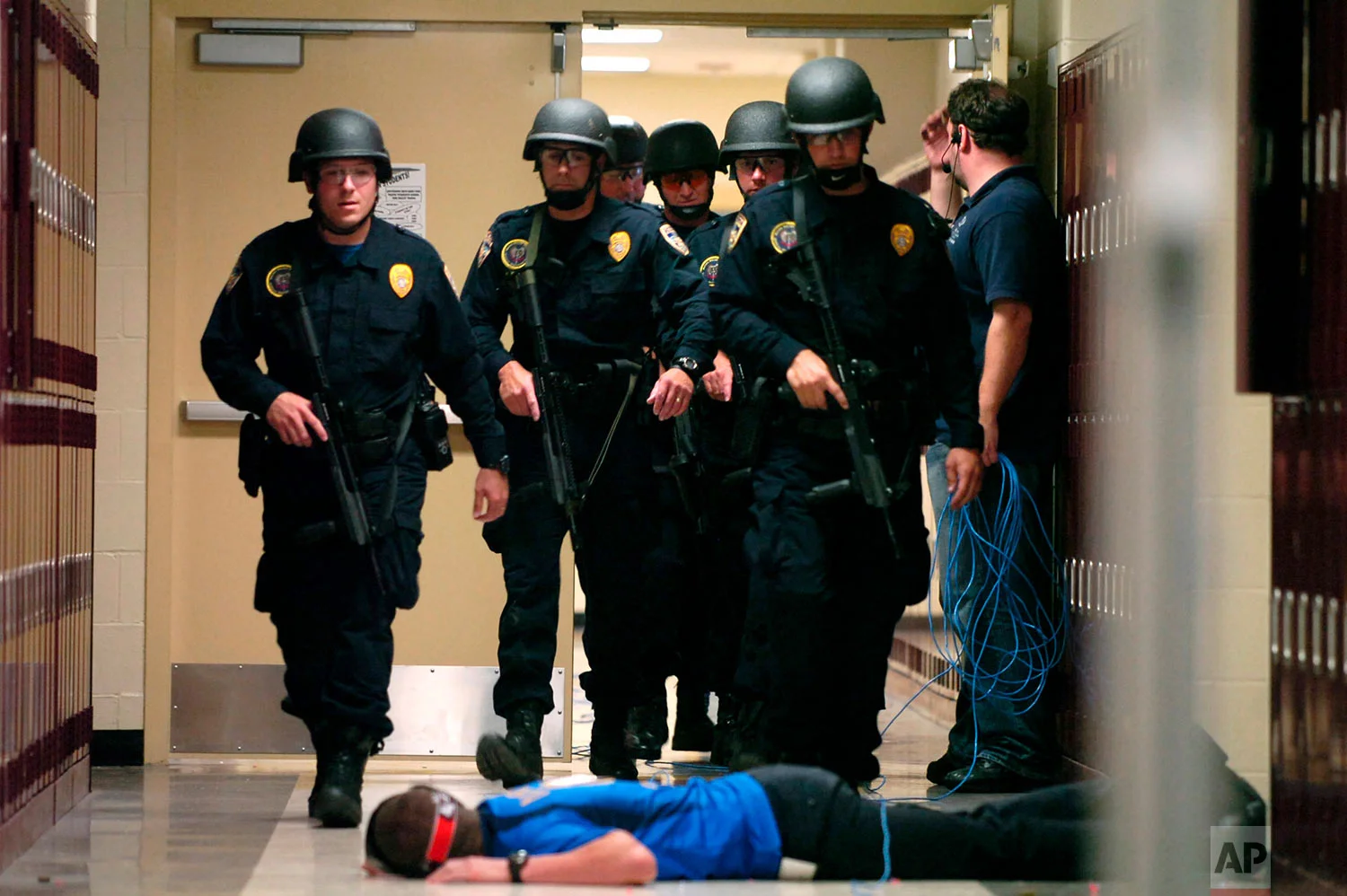 In this May 29, 2008 photo, Baton Rouge Police Department SWAT team members walk down a McKinley Middle Magnet School hallway past a fire academy member playing the role of a victim during a simulated hostage situation in Baton Rouge, La. High-tech hardware installed by NetTalon Security Systems reduced "casualties" during the exercise, according to then-principal Herman Brister. But in hindsight, he said he would have rather hired an armed resource officer. (Richard Alan Hannon/The Advocate via AP)