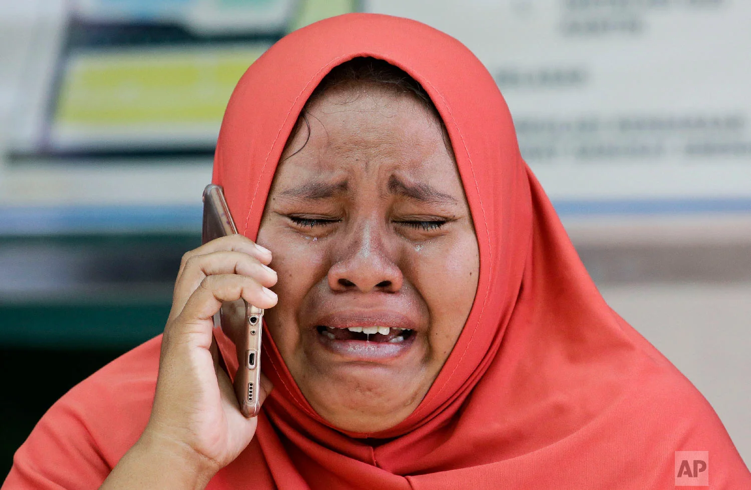 A woman cries as she uses the recovered mobile phone of her daughter who was killed in the earthquake at Palu, Central Sulawesi, Indonesia on Oct. 4, 2018. (AP Photo/Aaron Favila)