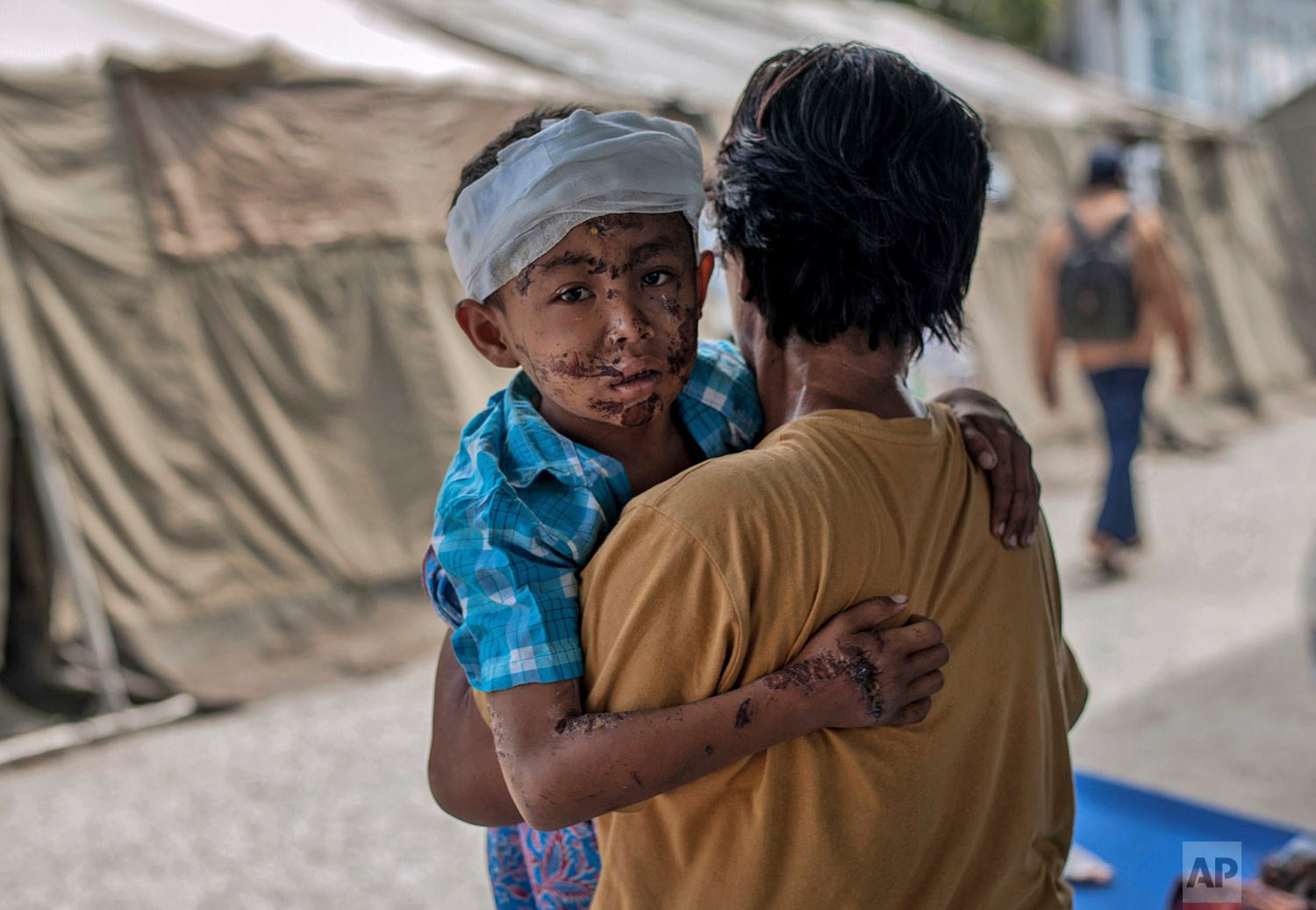 A boy injured during the tsunami is carries by his relative at a makeshift hospital in Palu, Central Sulawesi, Indonesia, Oct. 4, 2018. (AP Photo/Fauzy Chaniago)