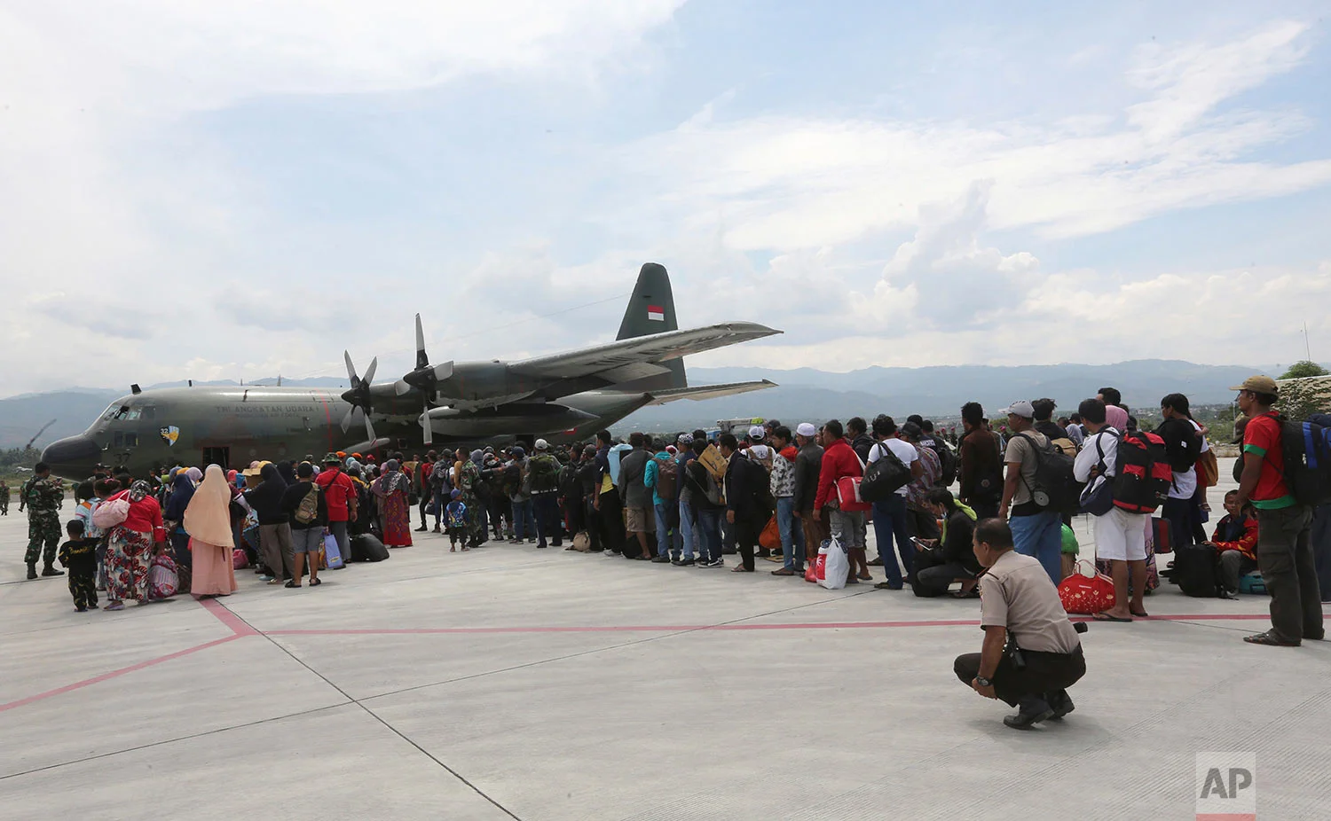 People line up to board an Indonesian Air Force cargo plane at Mutiara Sis Al-Jufri airport as they try to go out of Palu, Central Sulawesi Indonesia, Oct. 4, 2018. (AP Photo/Tatan Syuflana)