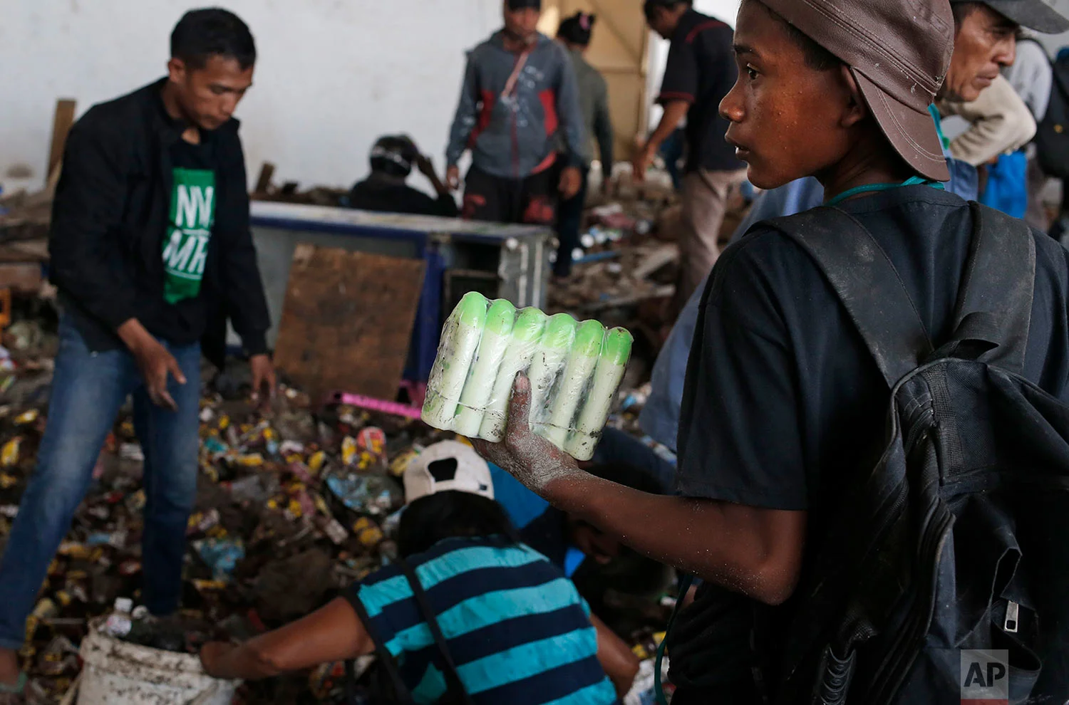 A man holds bottles of body lotions he scavenged from an abandoned warehouse at an earthquake and tsunami-affected area in Palu, Central Sulawesi, Indonesia Indonesia, Oct. 3, 2018. (AP Photo/Dita Alangkara)