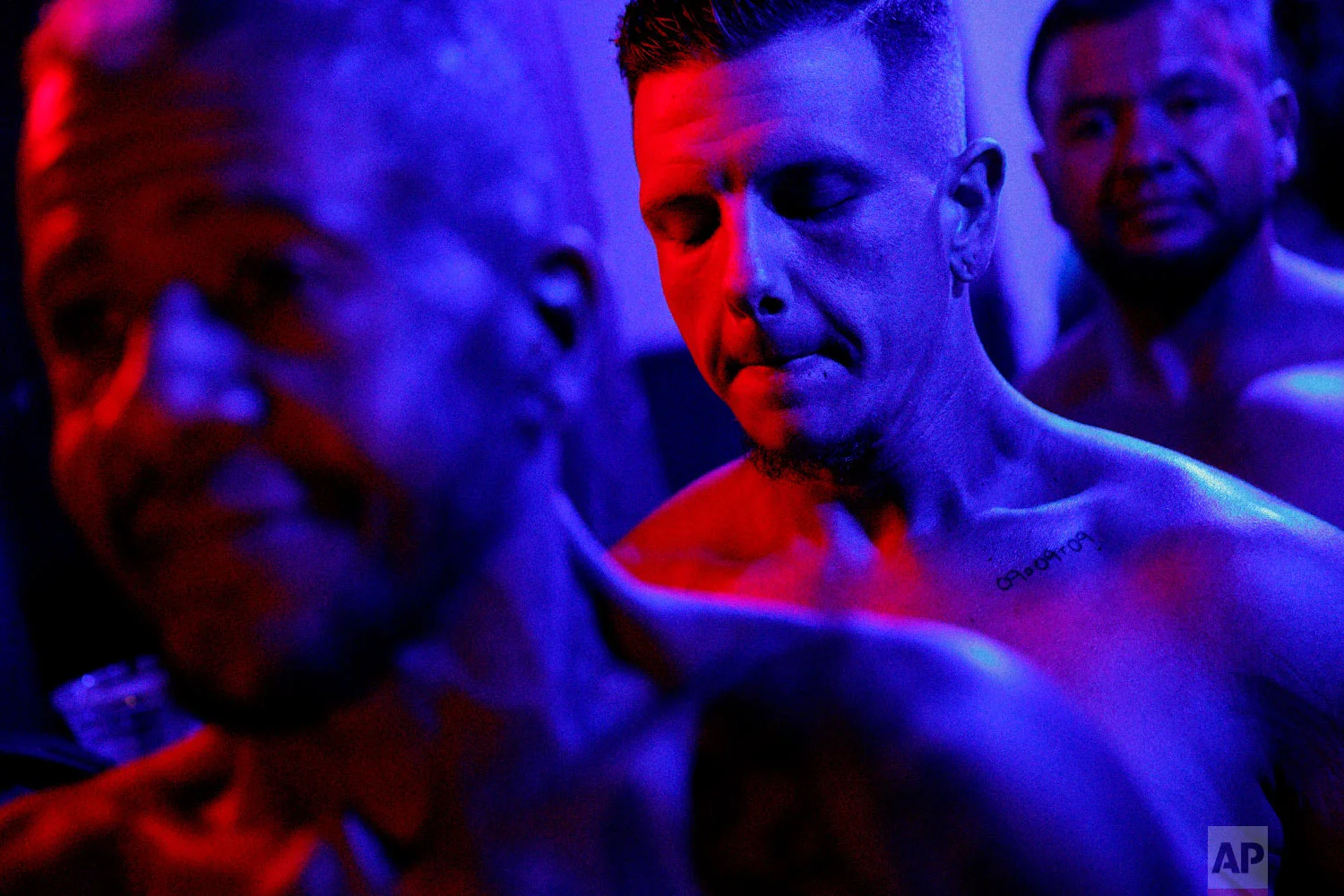 Devyn Michael Clark, of Jacksonville, Fla., center, closes his eyes for a moment backstage before the start of the International Association of Trans Bodybuilders competition in Atlanta, Oct. 6, 2018. (AP Photo/David Goldman)