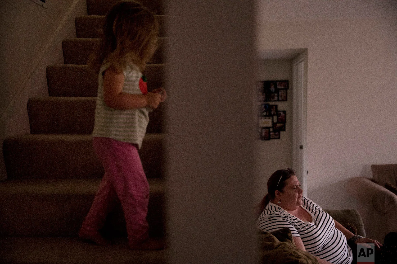 Middle-school English teacher Maryam Powers sits in her sofa as her 2-year-old daughter walks up the steps leading to the master bedroom in Salinas, Calif., on Sept. 5, 2018. (AP Photo/Jae C. Hong)