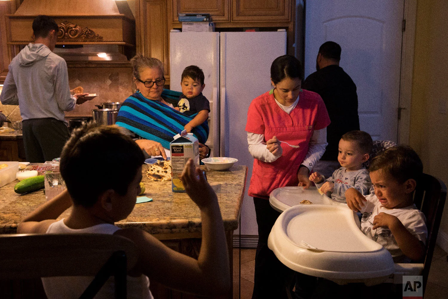 Lilia Coyt, center left, and Coyt's daughter-in-law, Araceli Nunez, feed babies in their four-bedroom home, where three generations and 15 members of the family are jammed into, in Salinas, Calif. (AP Photo/Jae C. Hong)