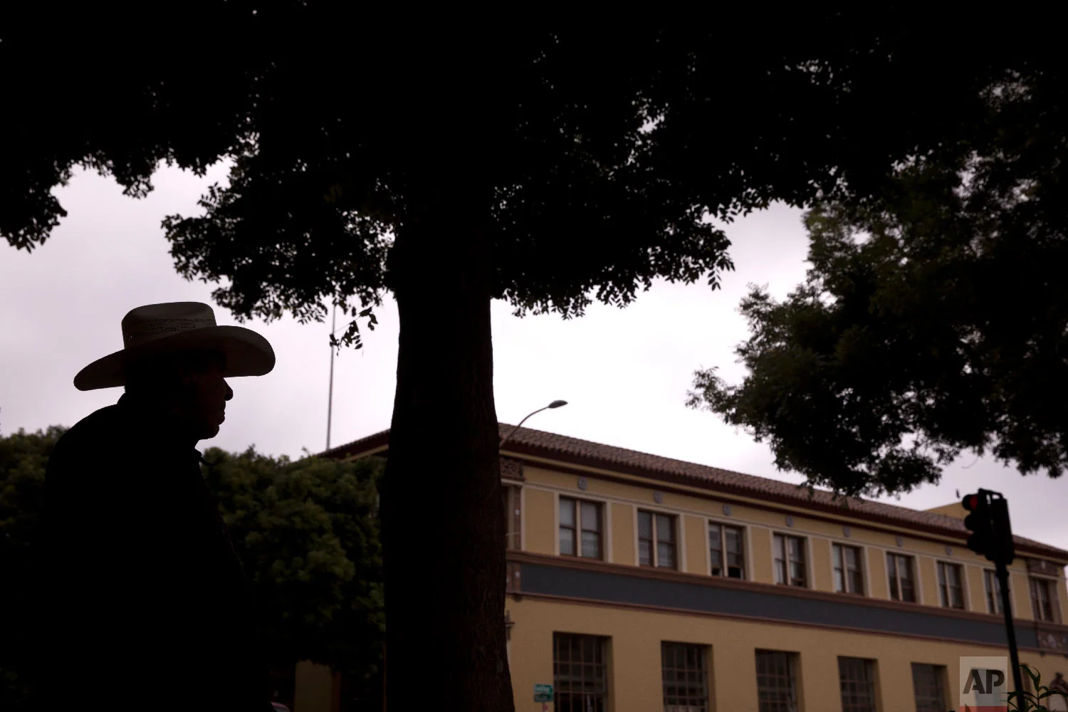 Retired farmworker Alberto Alvarez, 70, is silhouetted as he strolls around downtown Salinas, Calif., Sept. 5, 2018. (AP Photo/Jae C. Hong)