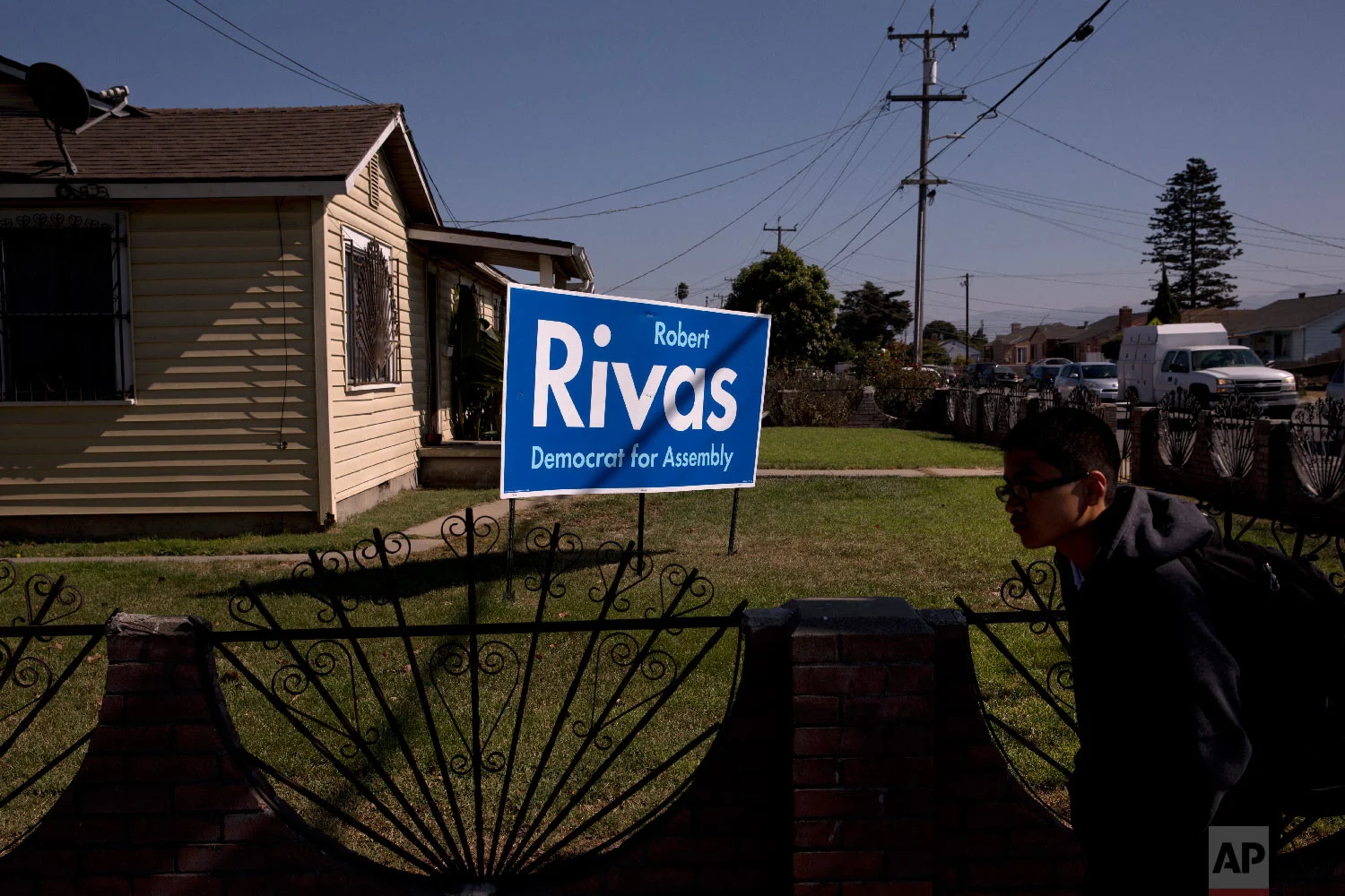 A student walks past a lawn sign supporting Robert Rivas, a Democratic candidate for California's 30th State Assembly District in Salinas, Calif., Sept. 6, 2018. (AP Photo/Jae C. Hong)