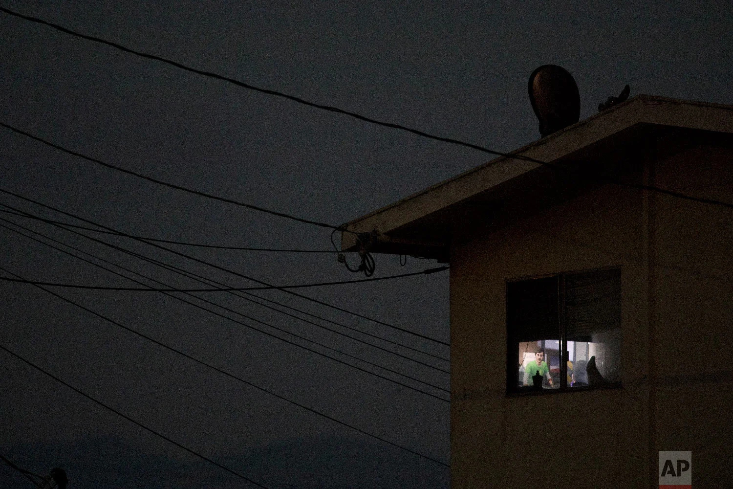 Electrical wires run into an apartment building as a room is lit by a TV screen in Salinas, Calif., Sept. 6, 2018. (AP Photo/Jae C. Hong)