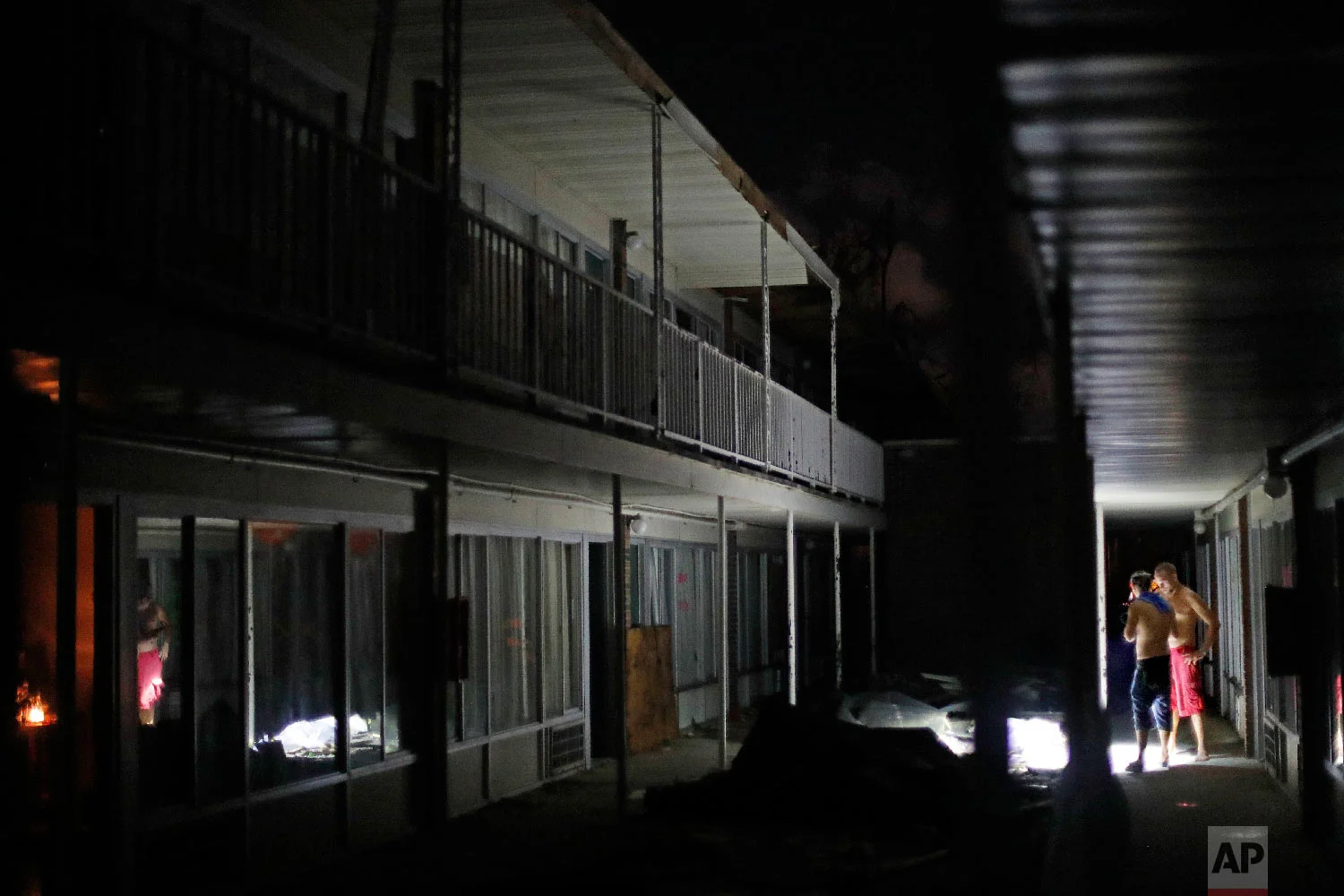 Residents use flashlights to navigate the dark walkways at night at the damaged American Quality Lodge where they continue to live in the aftermath of Hurricane Michael, in Panama City, Fla., Oct. 16, 2018. (AP Photo/David Goldman)