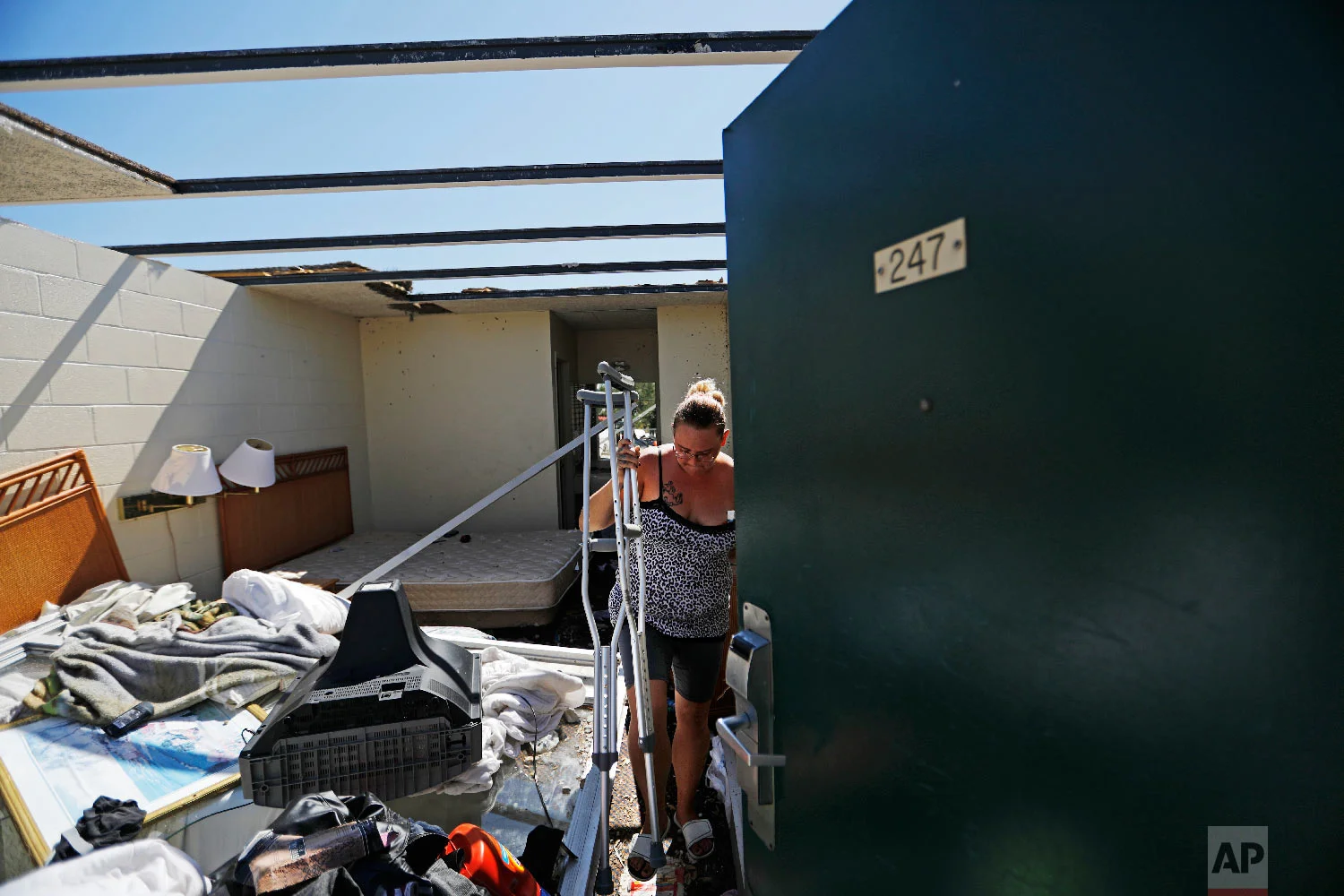 Jeannie Holcombe retrieves crutches for someone in need from a damaged room at the American Quality Lodge in the aftermath of Hurricane Michael, in Panama City, Fla., Oct. 16, 2018. (AP Photo/David Goldman)