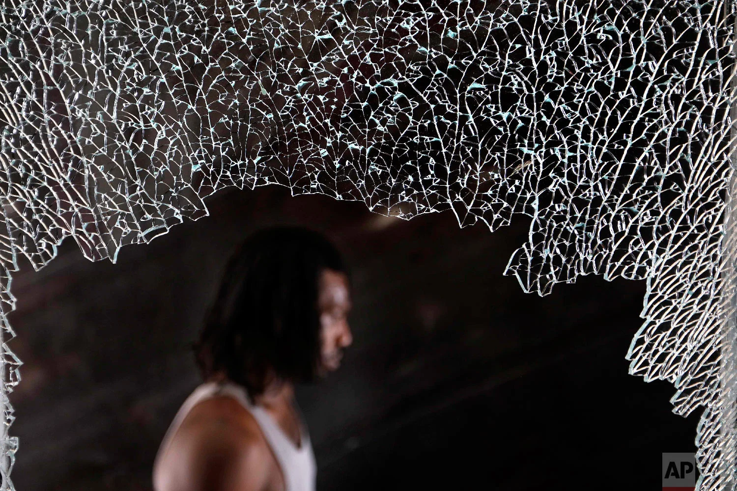A resident walks past a shattered window of a room at a damaged motel, Oct. 16, 2018, in Panama City, Fla., where guests continue to stay in the aftermath of Hurricane Michael. (AP Photo/David Goldman)
