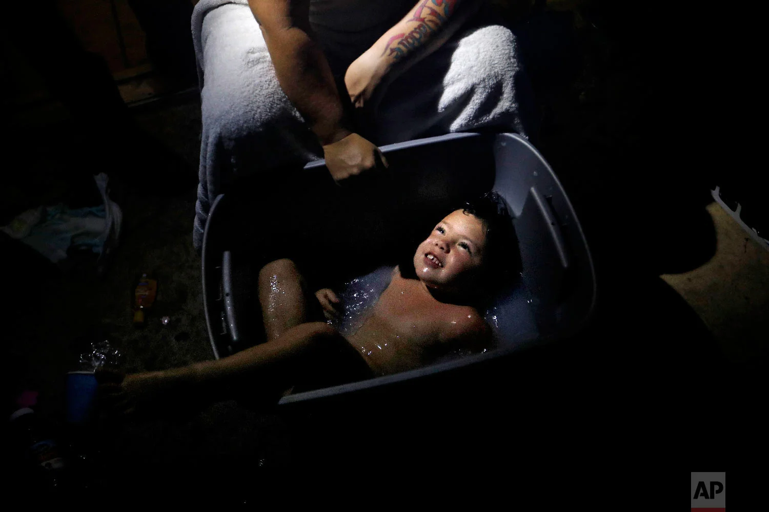 Tasha Hughes, bathes her daughter, Madison, 4, in a storage bin outside their room at the damaged American Quality Lodge where they continue to live without power in the aftermath of Hurricane Michael, in Panama City, Fla., Oct. 16, 2018. (AP Photo/David Goldman)