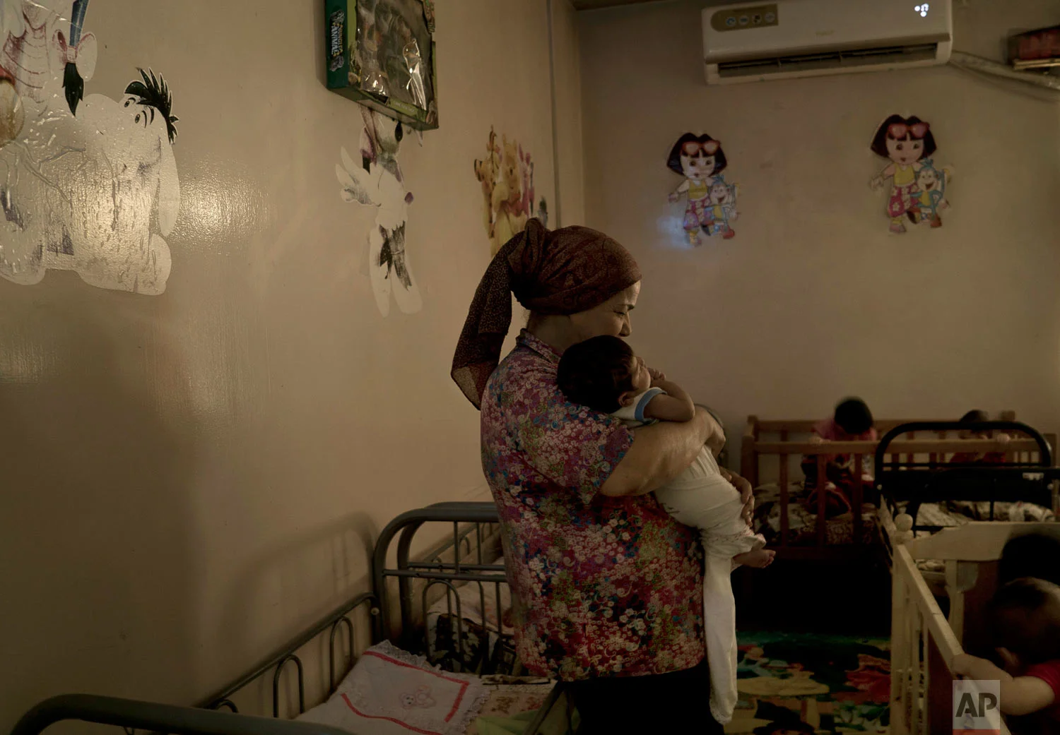 A caregiver soothes a newborn baby girl named Helen at the state-run Salhiya Orphanage in Baghdad, Iraq. (AP Photo/Maya Alleruzzo)