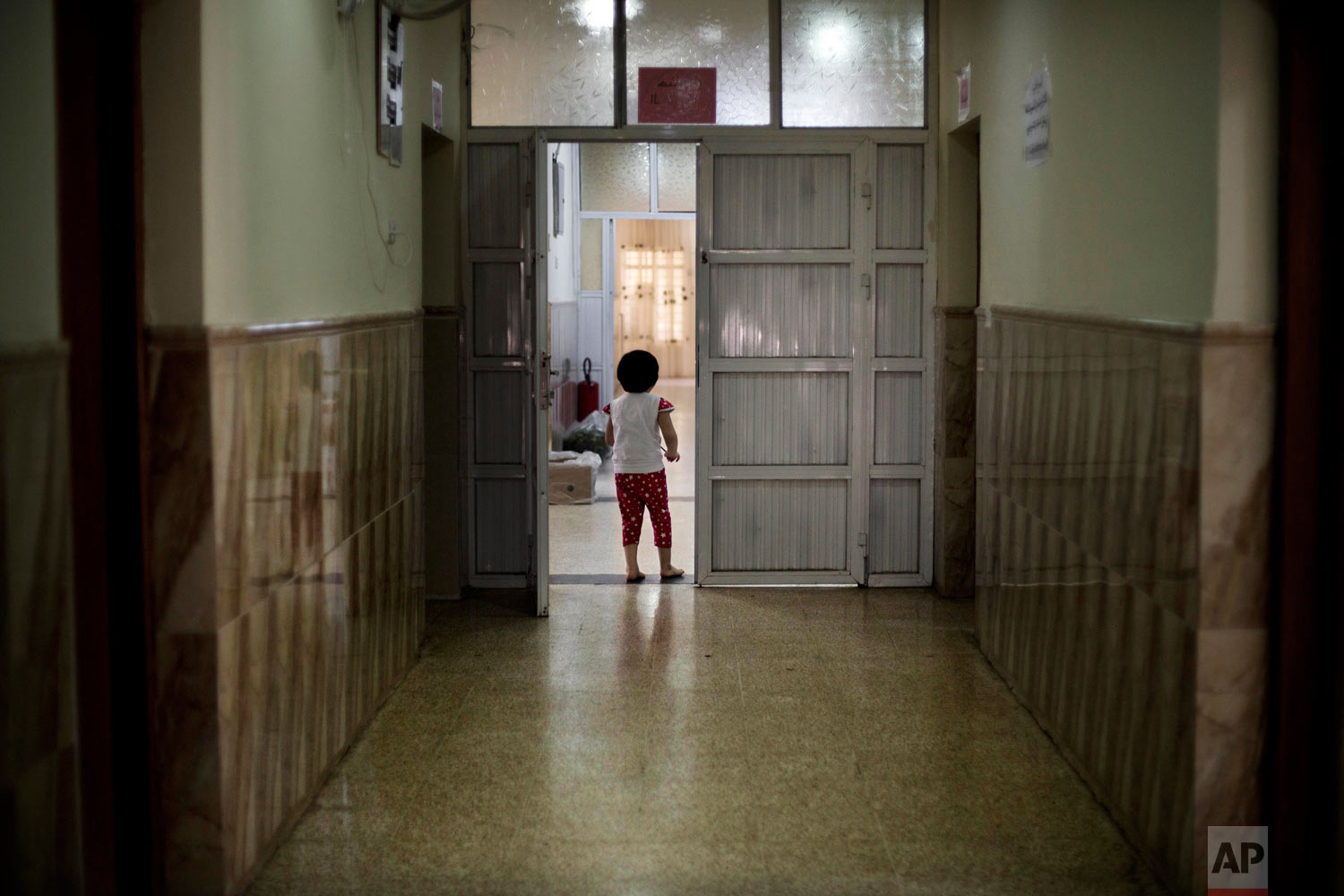  A girl wanders through a hallway at the state-run al-Zuhour orphanage in Mosul, Iraq. (AP Photo/Maya Alleruzzo) 